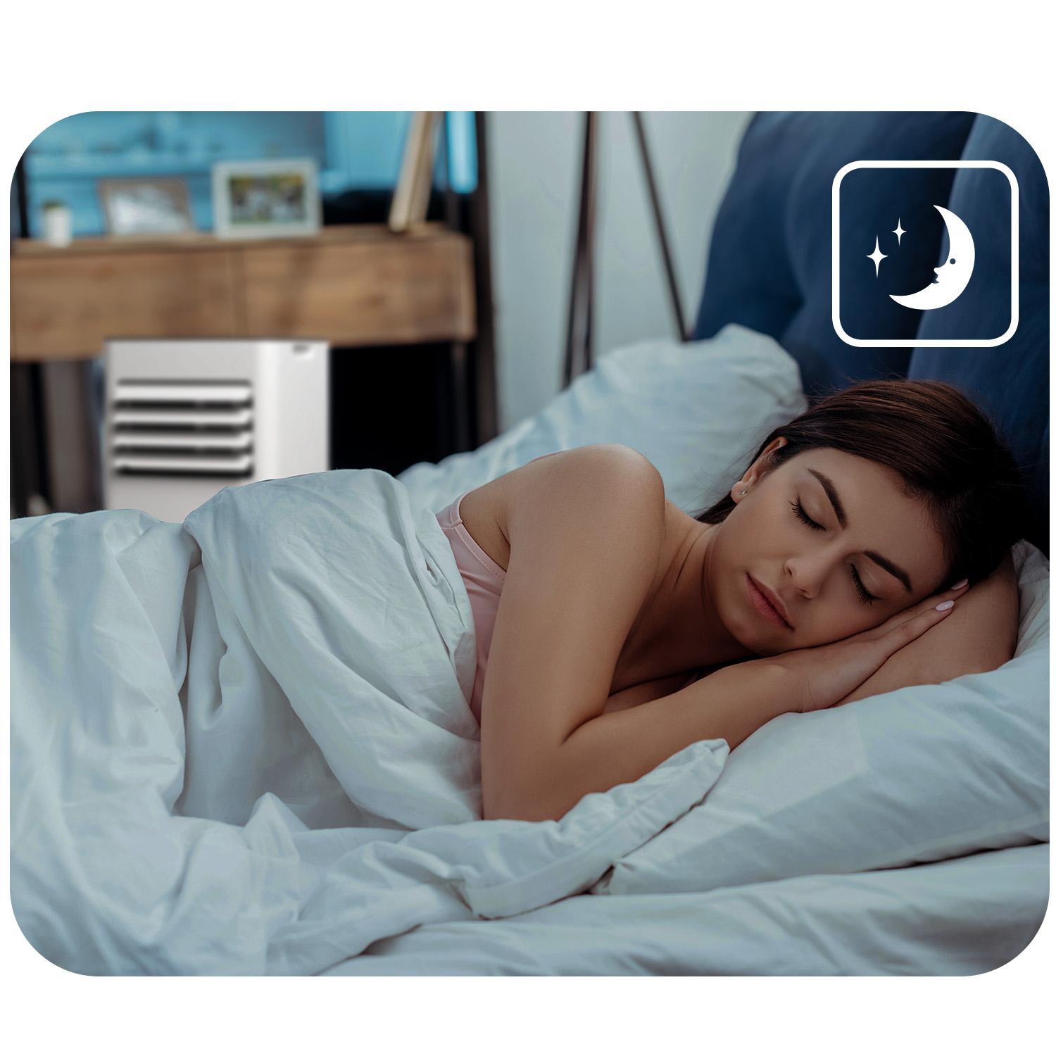 Kobieta śpi w łóżku, obok stoi chłodnica powietrza.