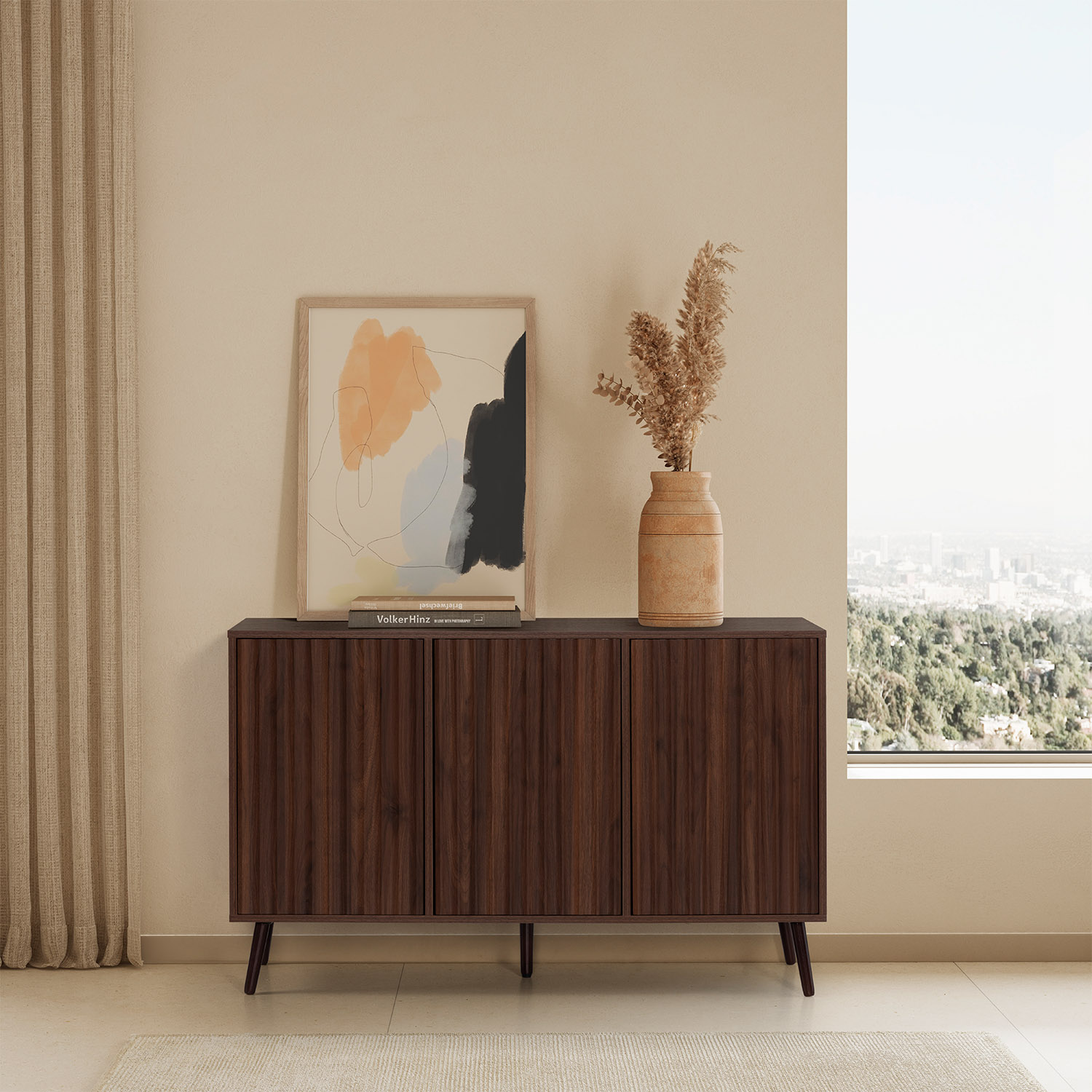 Un mueble de madera oscura con ranuras verticales se alza contra una pared. Encima hay un cuadro y un jarrón con flores secas.