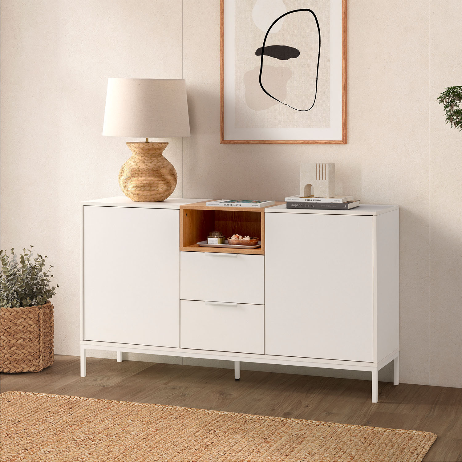 Un aparador blanco con detalles de madera, lámpara, obra de arte y planta.