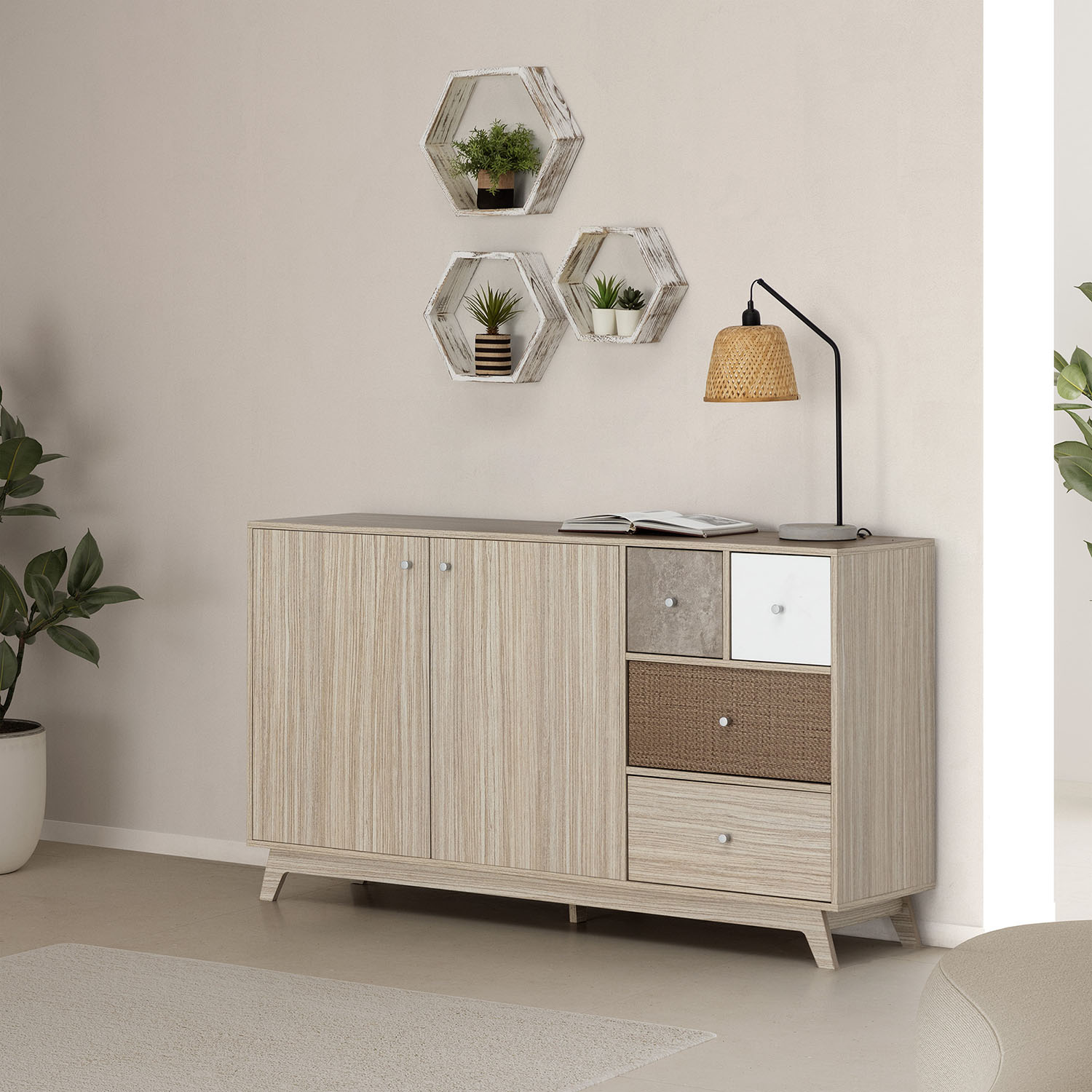 Un mueble de madera clara con cajones y puertas variados, libro y lámpara encima.