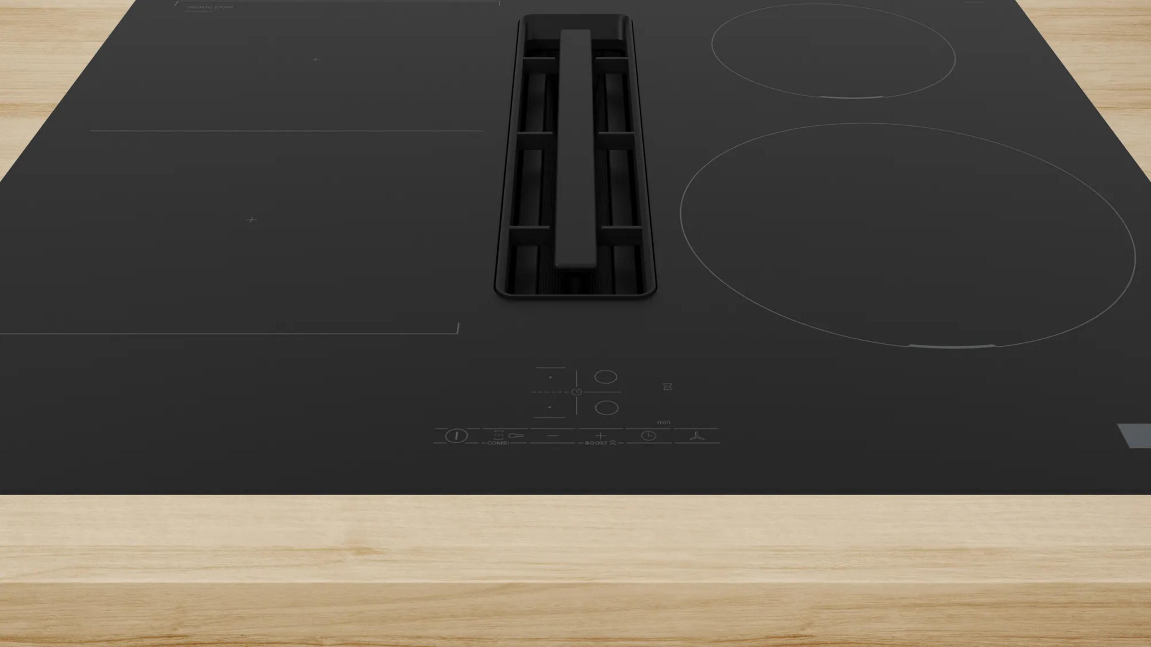 Une plaque à induction noire avec hotte aspirante centrale sur surface en bois.