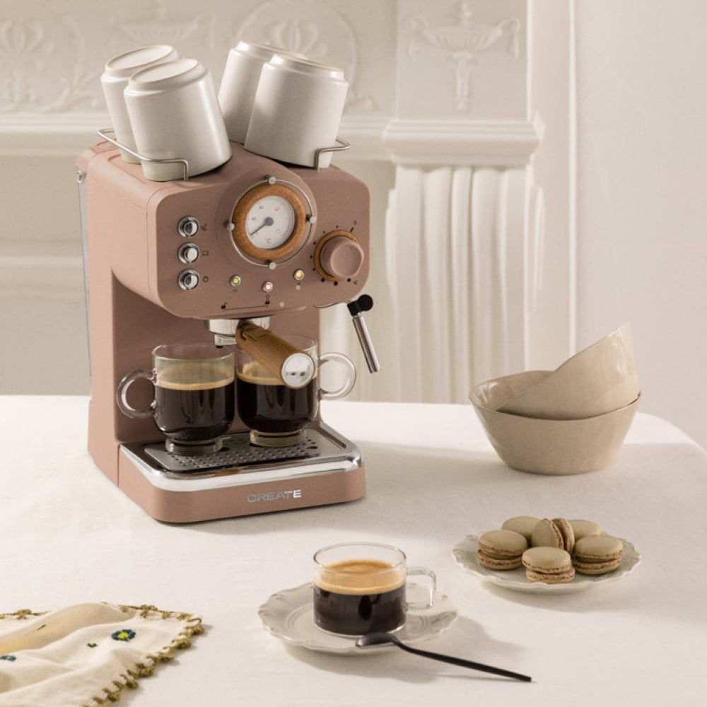 Una máquina de espresso rosa con dos tazas de café y cuatro tazas encima.
