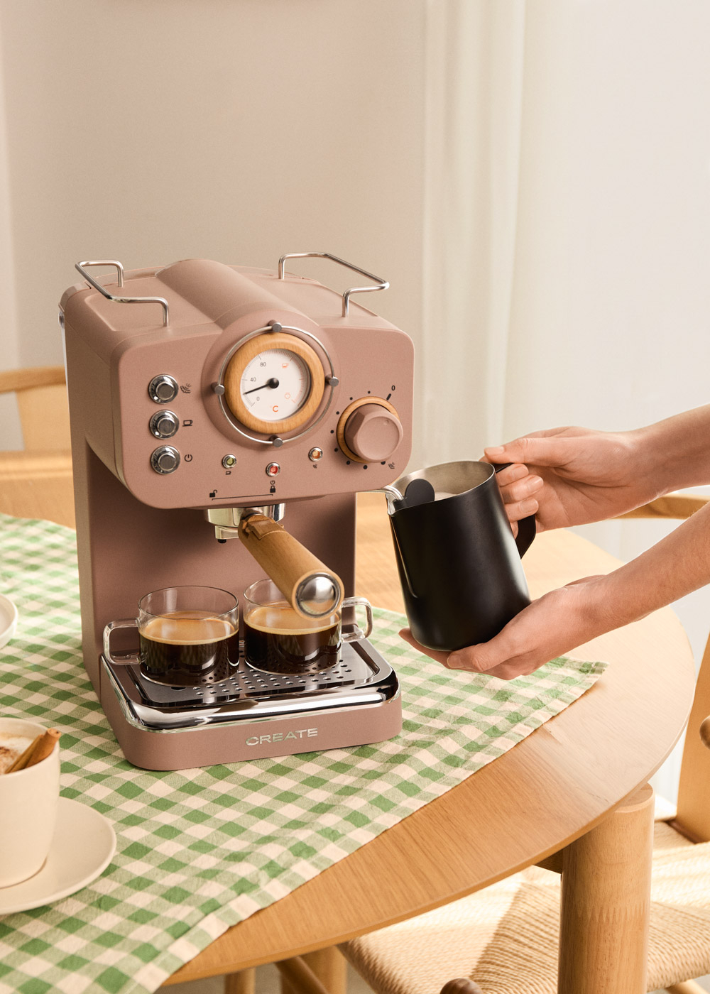 Una cafetera espresso color canela con dos tazas y jarra espumadora.