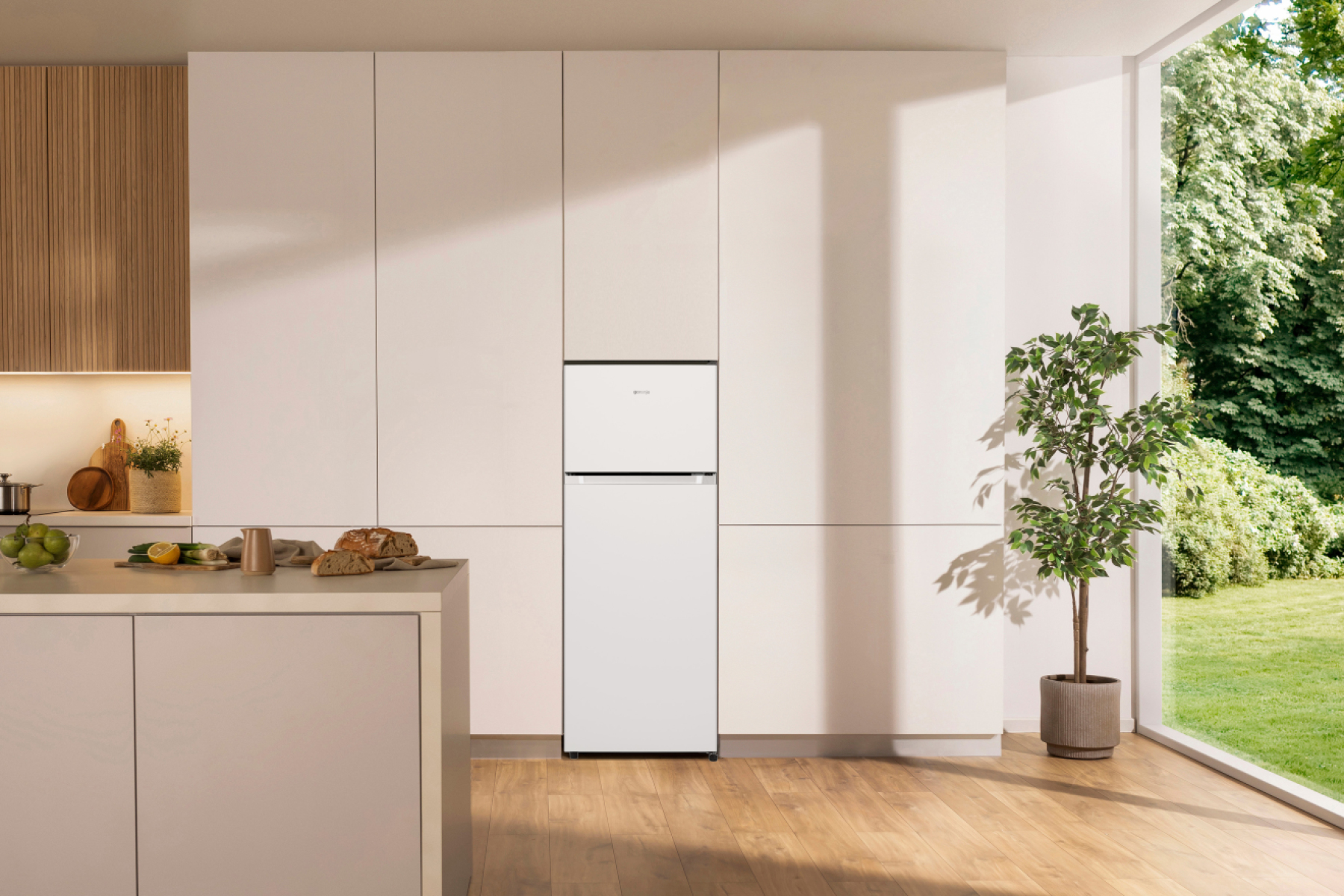 Eine weiße Kühlgefrierkombination steht in einer modernen Küche mit Holzböden.