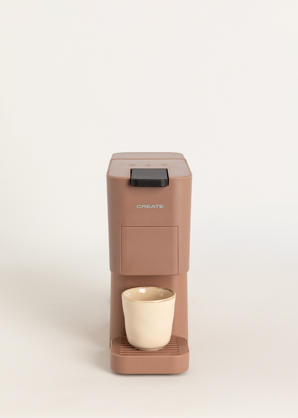 Una cafetera marrón con una taza beige en una bandeja de goteo. Fondo blanco.