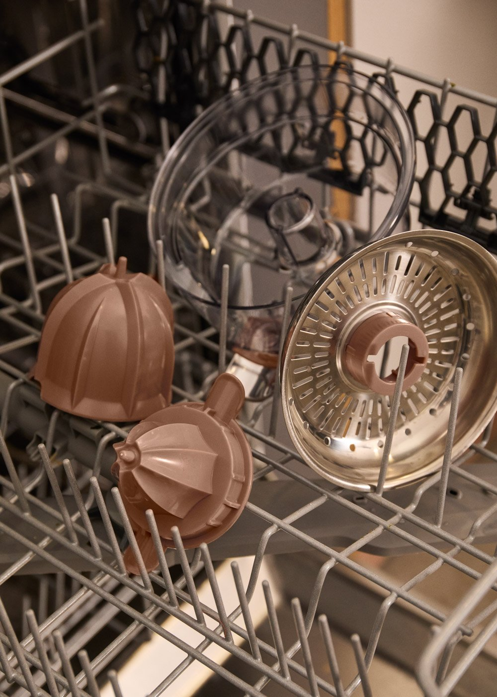 Accesorios de cocina marrones en una rejilla plateada de lavavajillas.