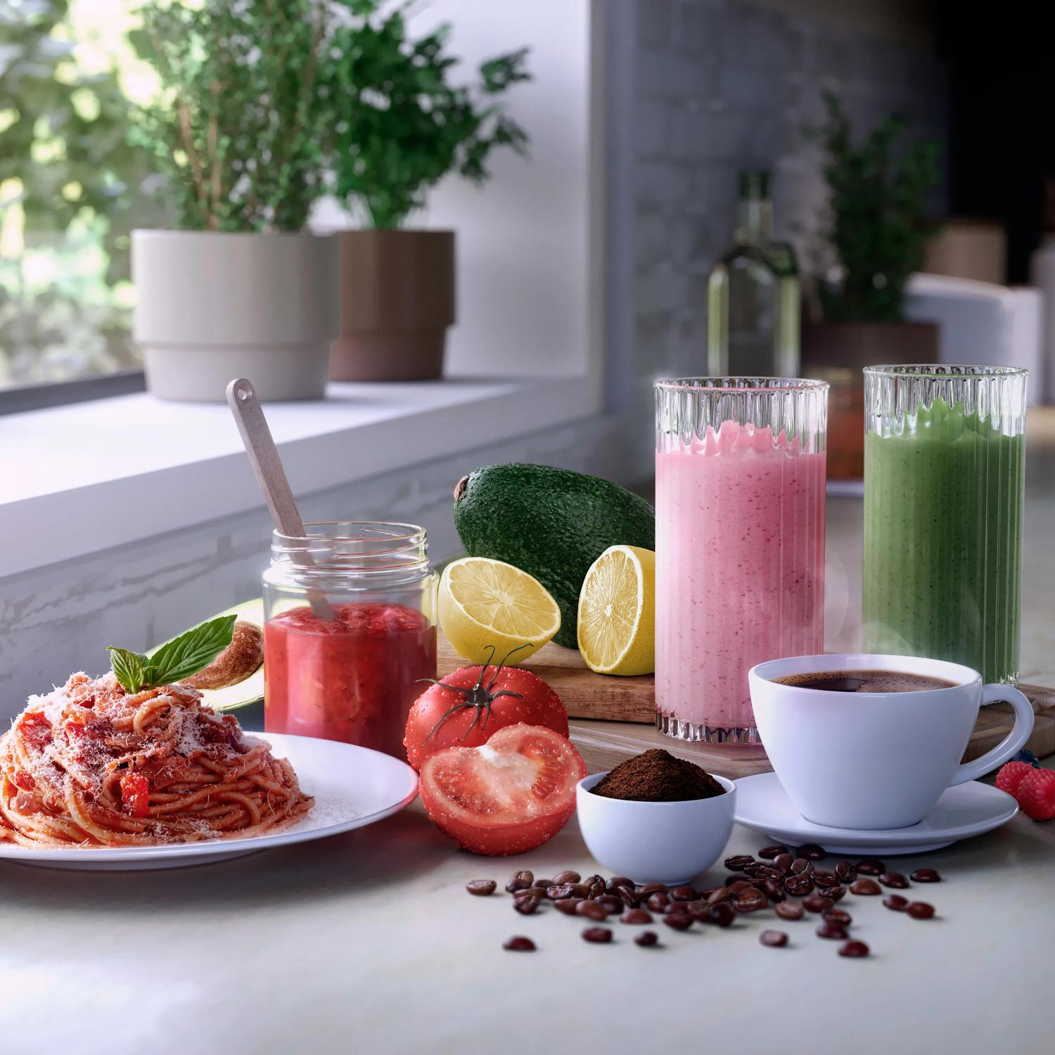 Spaghetti, coffee, smoothies, and fruit are arranged on a counter with plants in background.