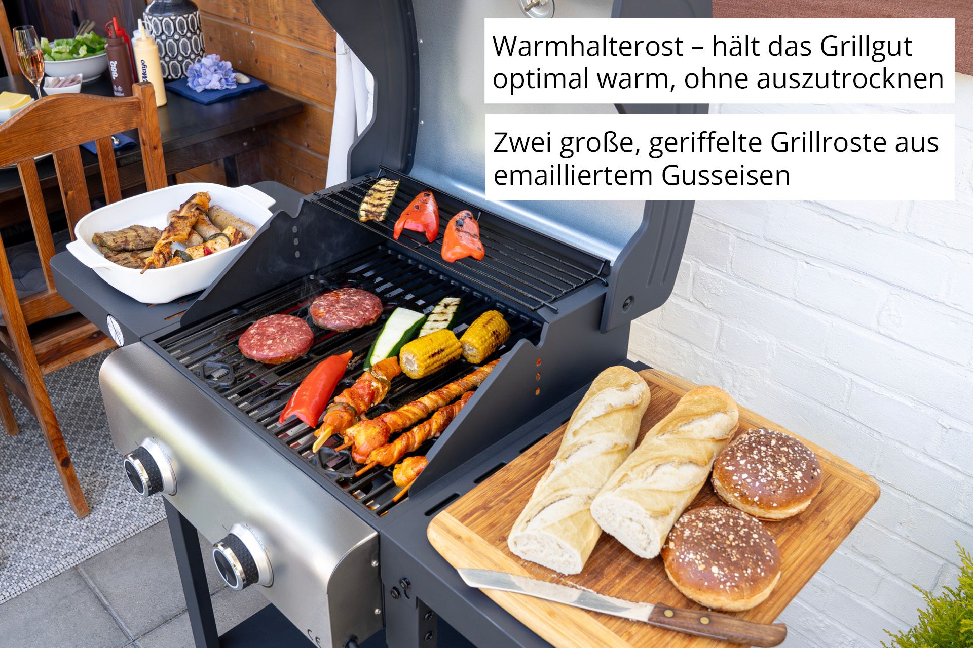Ein Grill mit Burgern, Spießen, Mais und Baguettes auf einem Holzbrett.