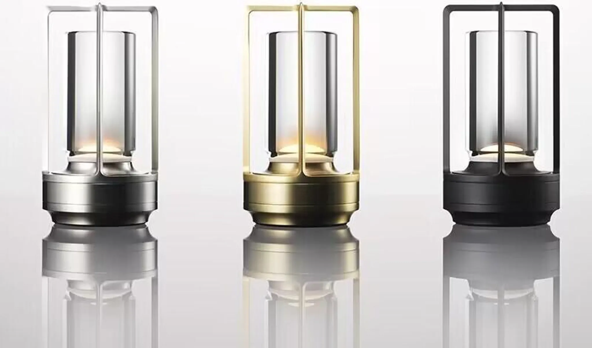 Drei moderne Laternen: eine silbern, eine goldfarben, eine schwarz, mit Glaszylindern.