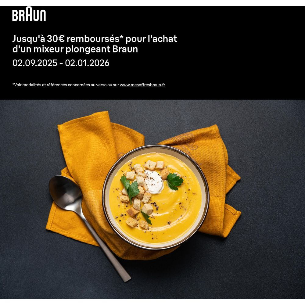 Una ciotola di zuppa cremosa con crostini, panna e prezzemolo, con un cucchiaio.