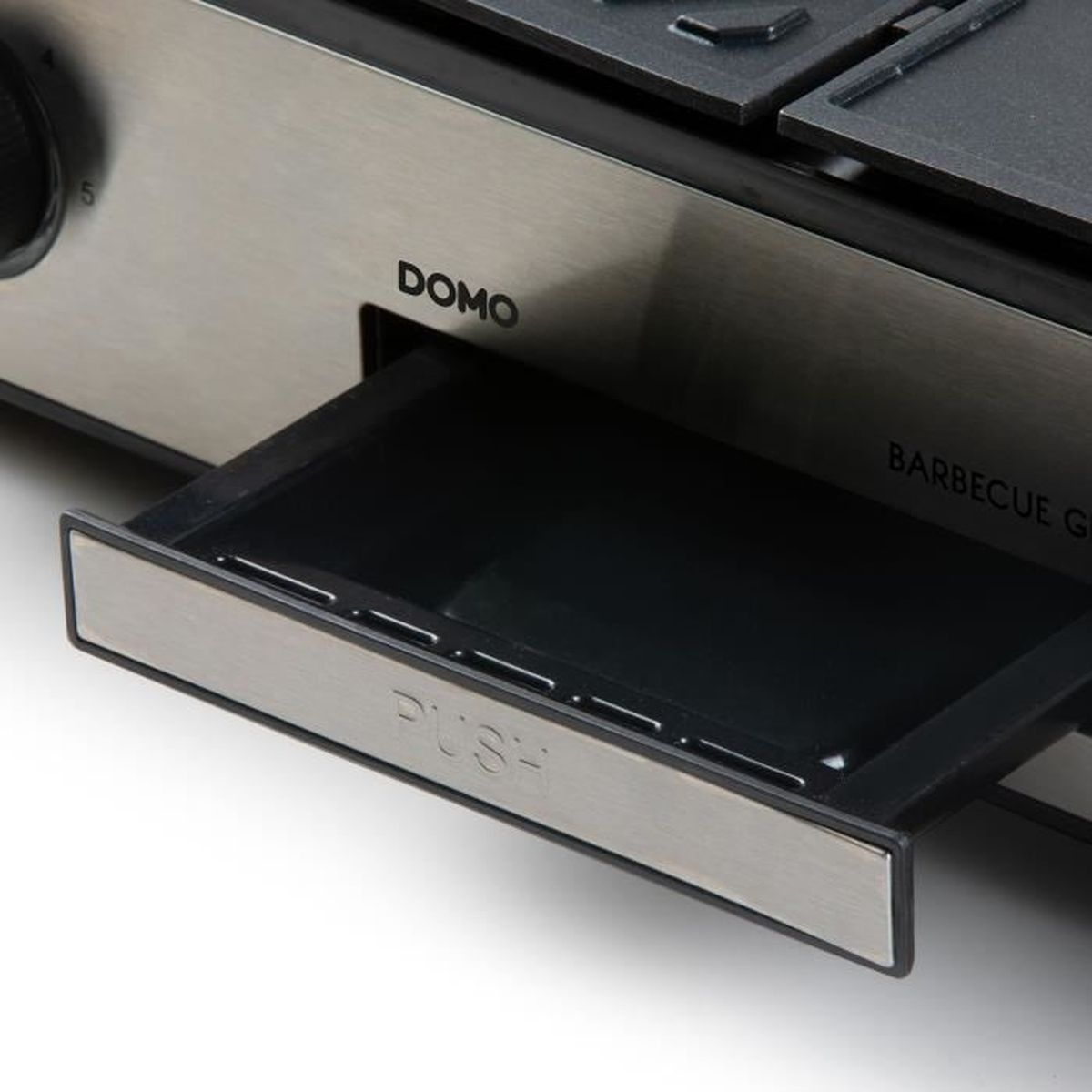 Primo piano di una griglia con cassetto estratto, con etichette "DOMO" e "PUSH".
