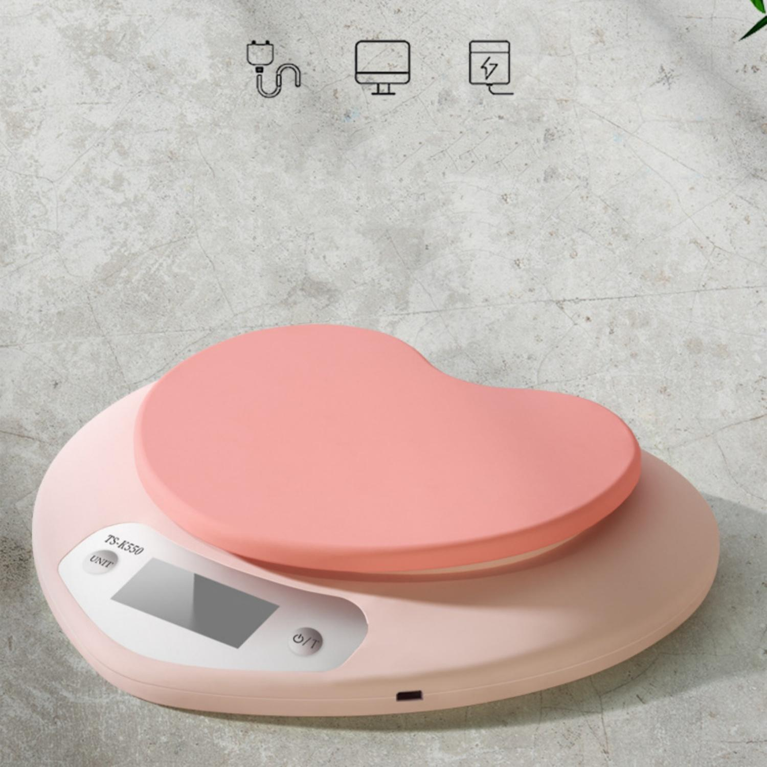 Eine rosa Herzform-Küchenwaage mit digitaler Anzeige auf Betonoberfläche.