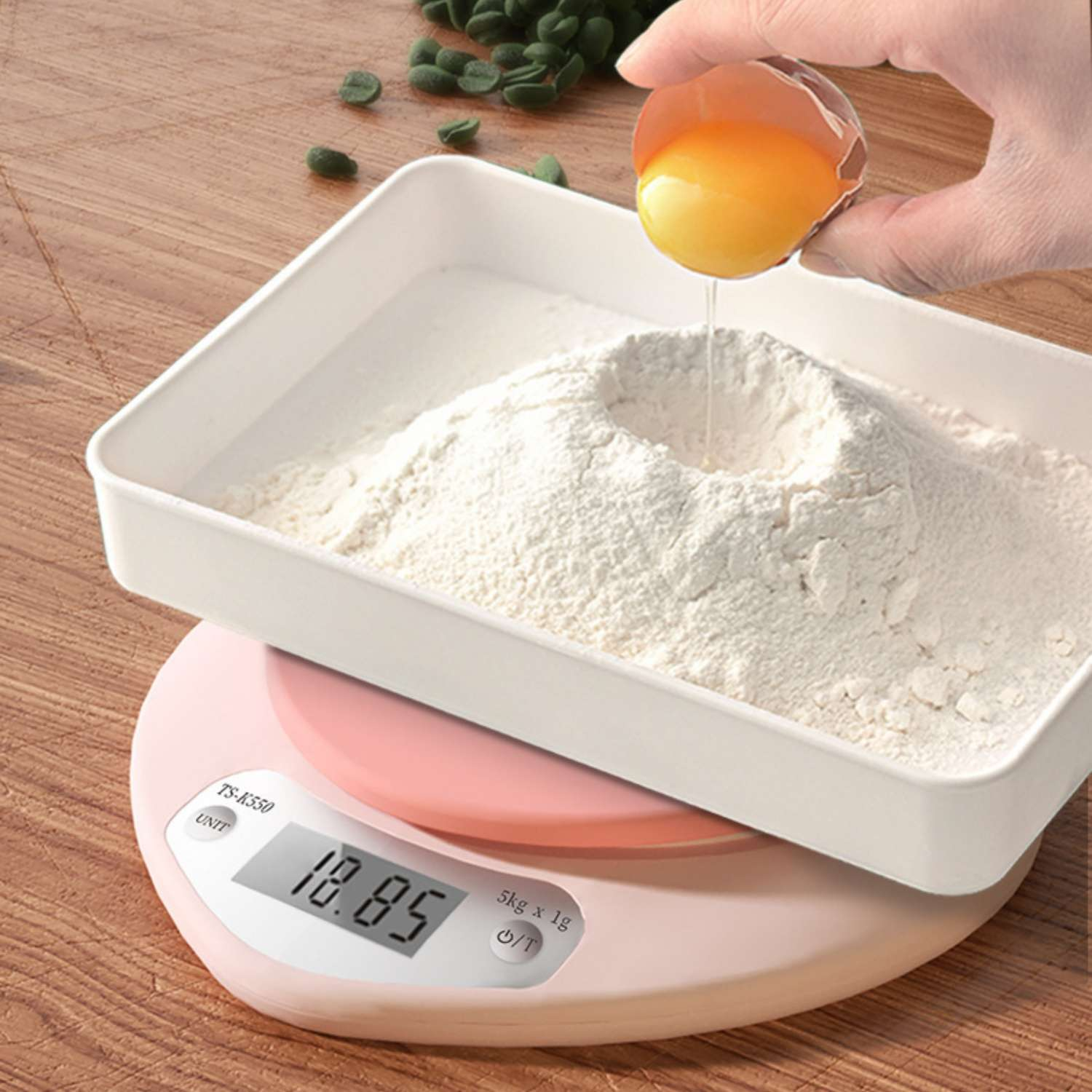 Ein Ei wird über eine Schüssel mit Mehl auf einer digitalen Küchenwaage gegossen.