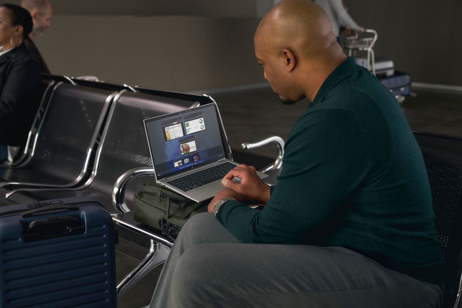Mężczyzna pracuje na laptopie w poczekalni lotniska z bagażem.