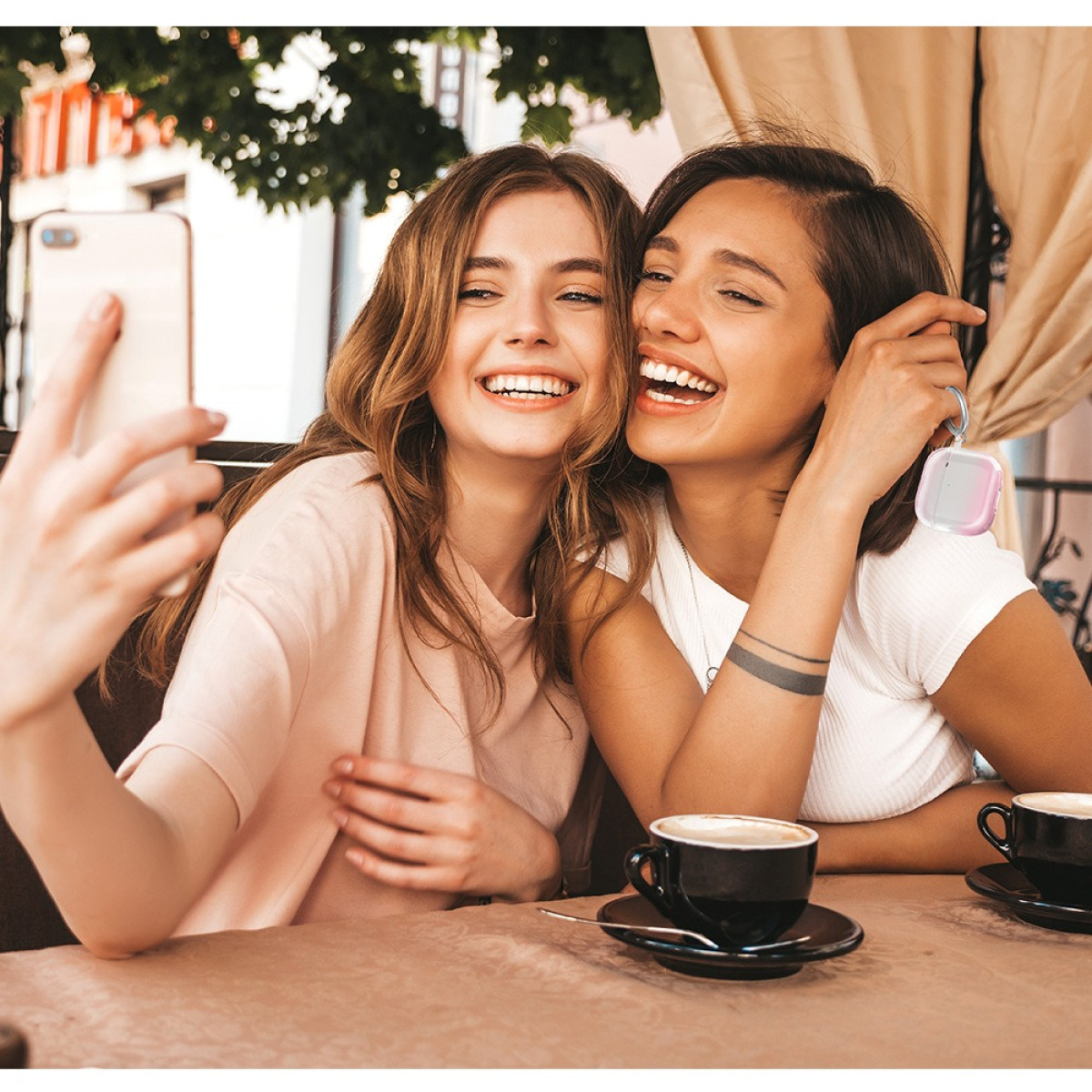 Zwei Frauen machen ein Selfie an einem Cafétisch mit Kaffeetassen.