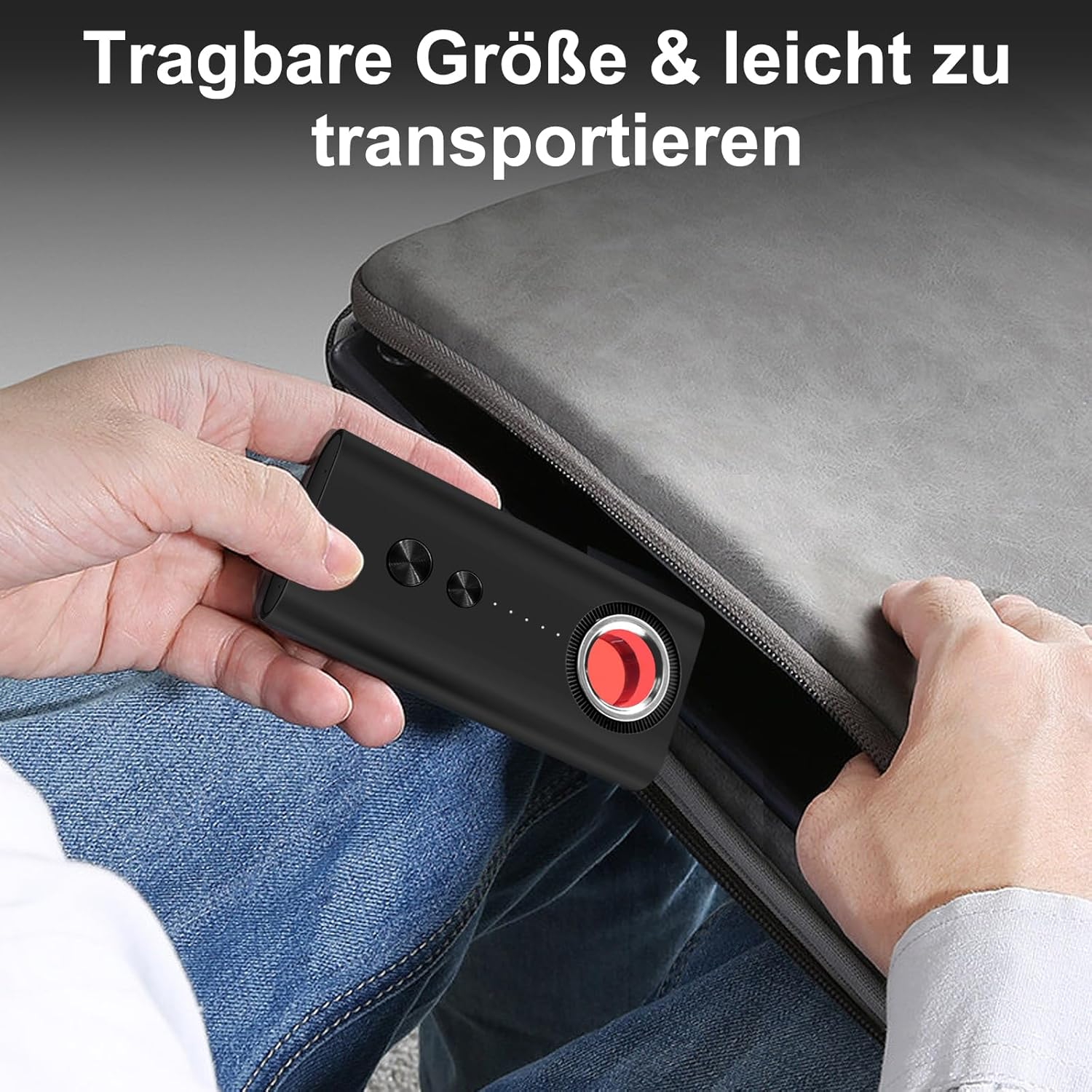 Eine Hand legt ein schwarzes tragbares Gerät mit rotem Knopf in eine graue Tasche.