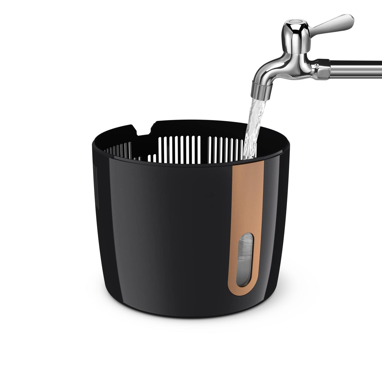 L'acqua scorre da un rubinetto cromato in un contenitore nero con accento di rame.