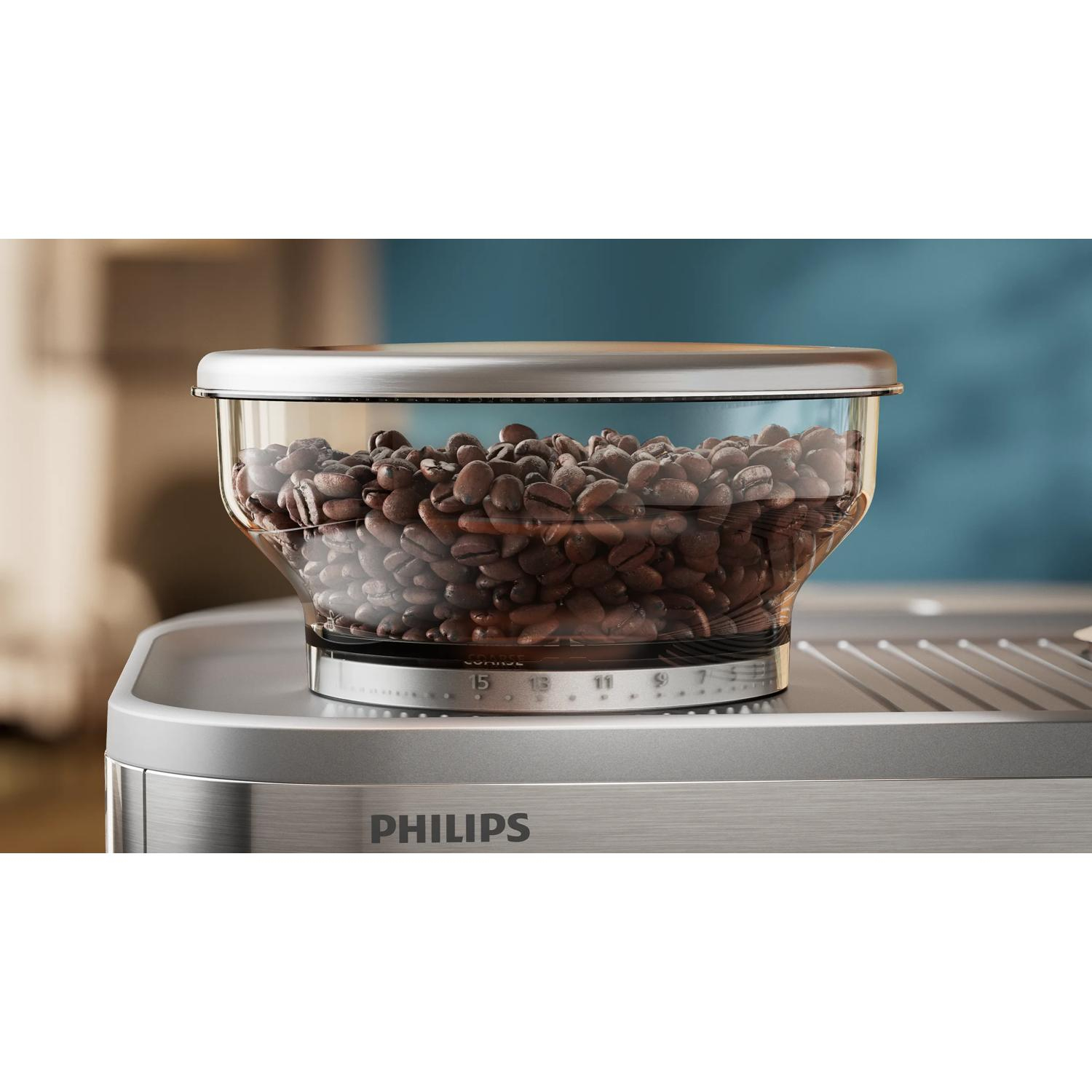 Szklany pojemnik wypełniony ziarnami kawy stoi na srebrnej maszynie do kawy Philips.