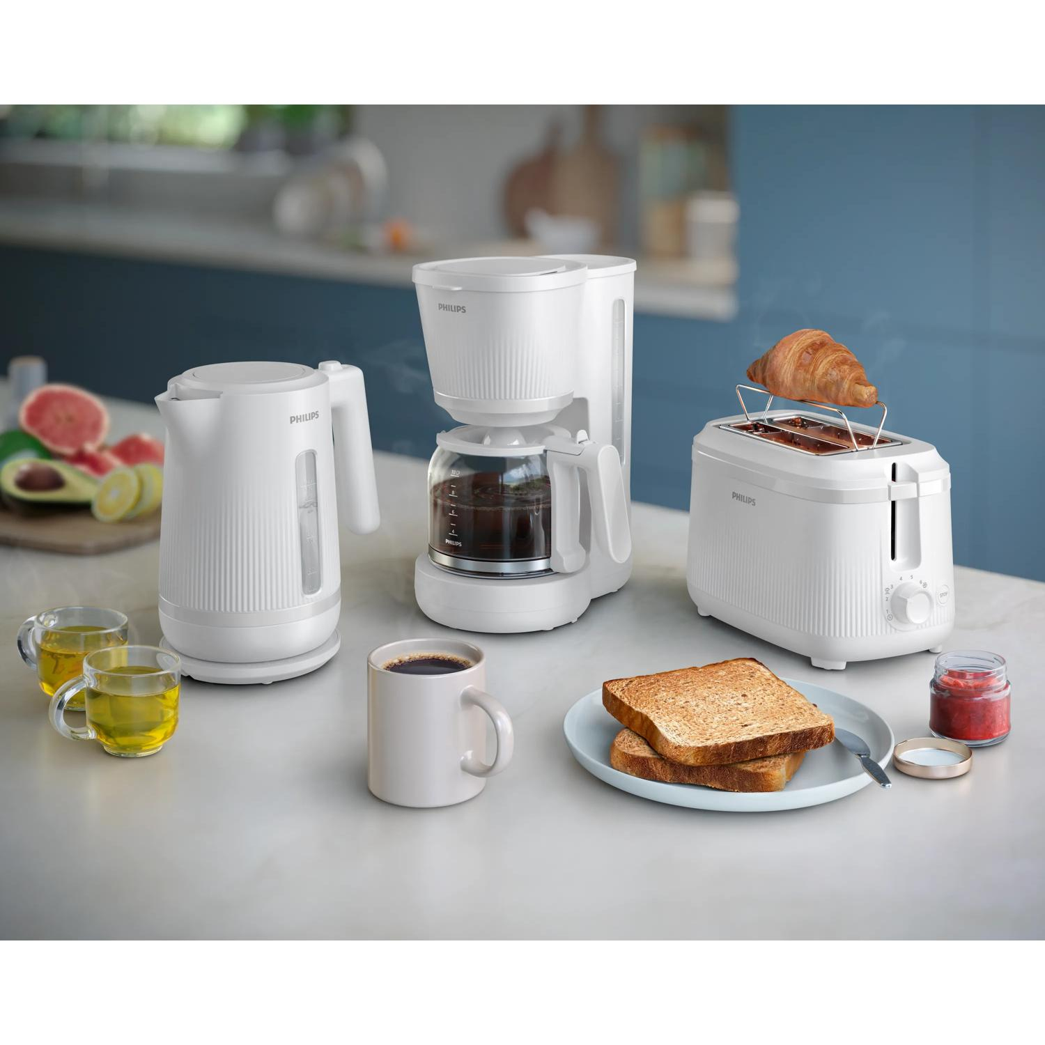 Weiße Küchengeräte: Wasserkocher, Kaffeemaschine, Toaster mit Croissant.