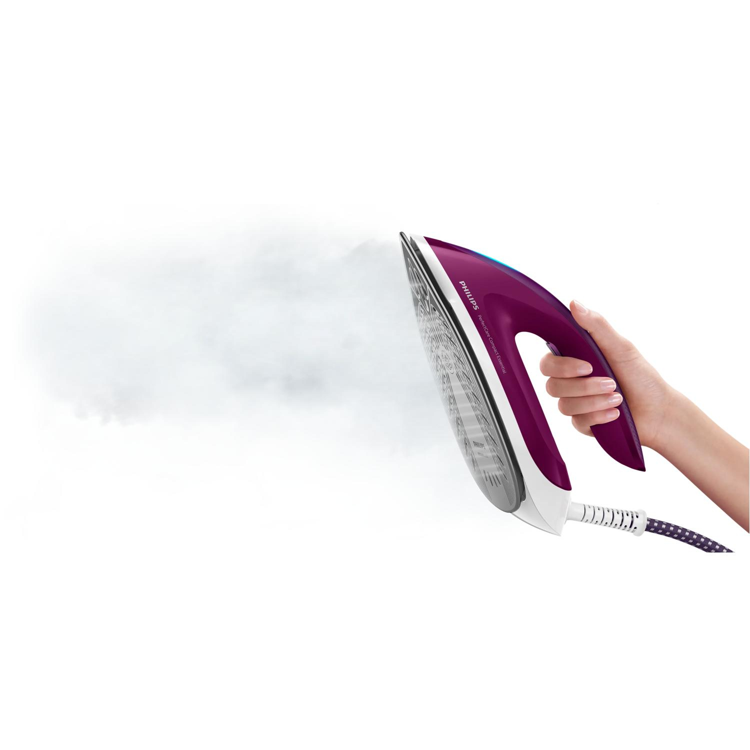 Una mano sostiene una plancha de vapor morada que emite vapor.