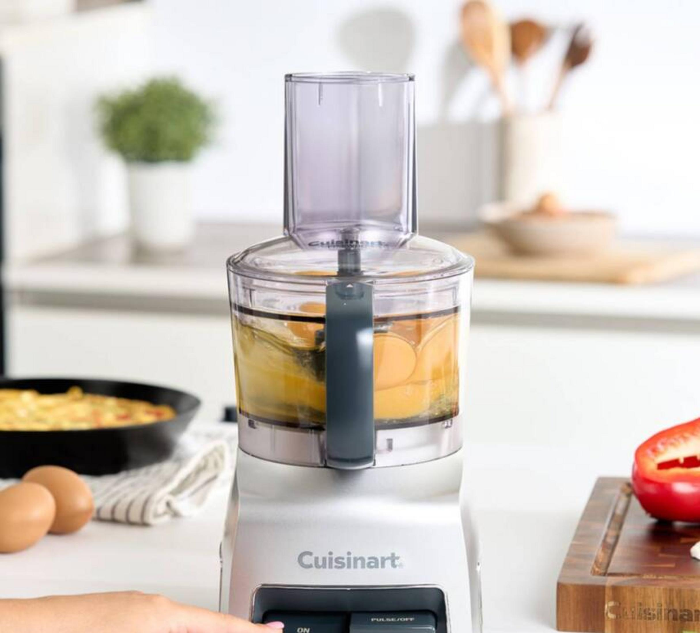 Un robot da cucina Cuisinart con uova e liquido nella ciotola, accanto a una frittata.