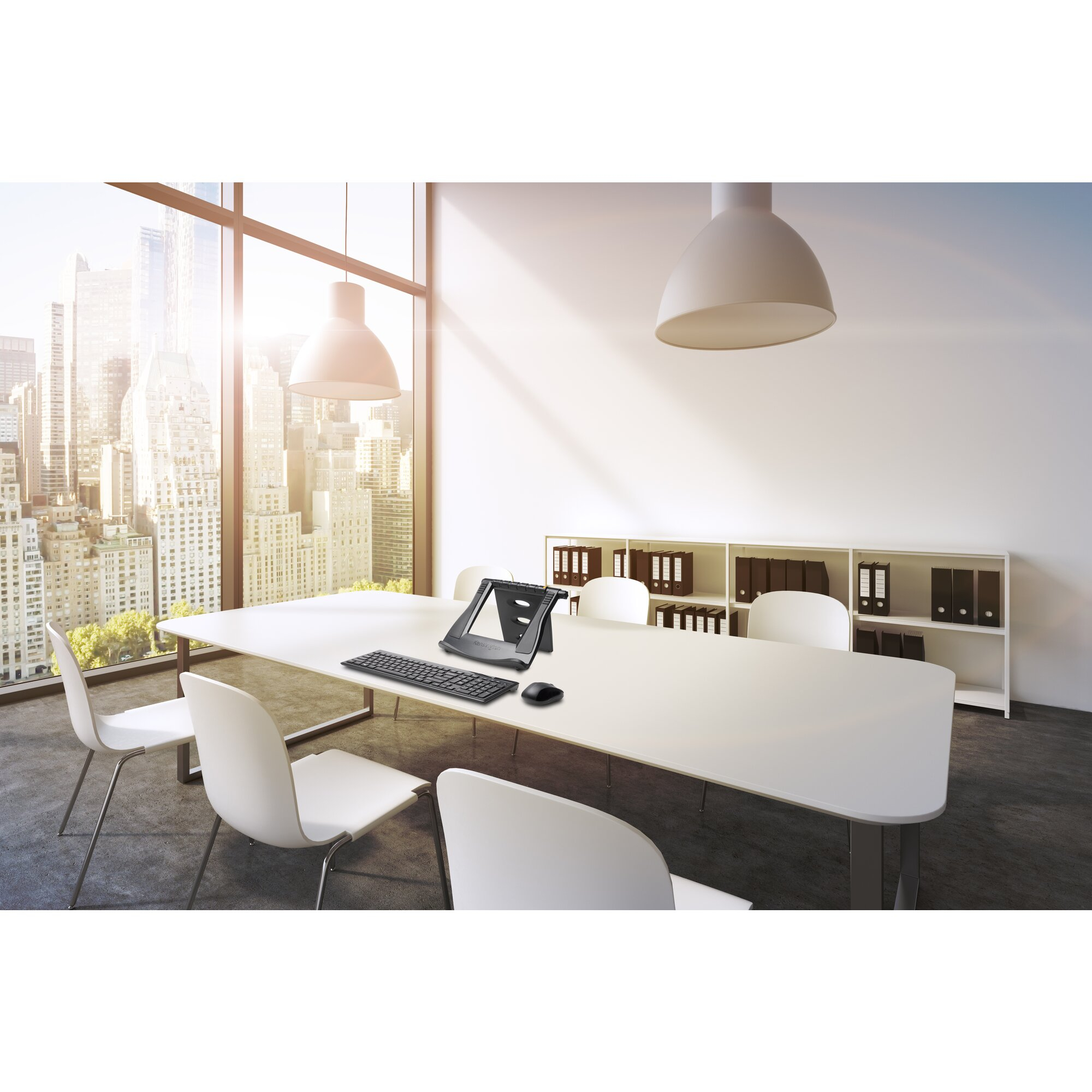 A modern office space with a large window, table with laptop stand, keyboard, and mouse.