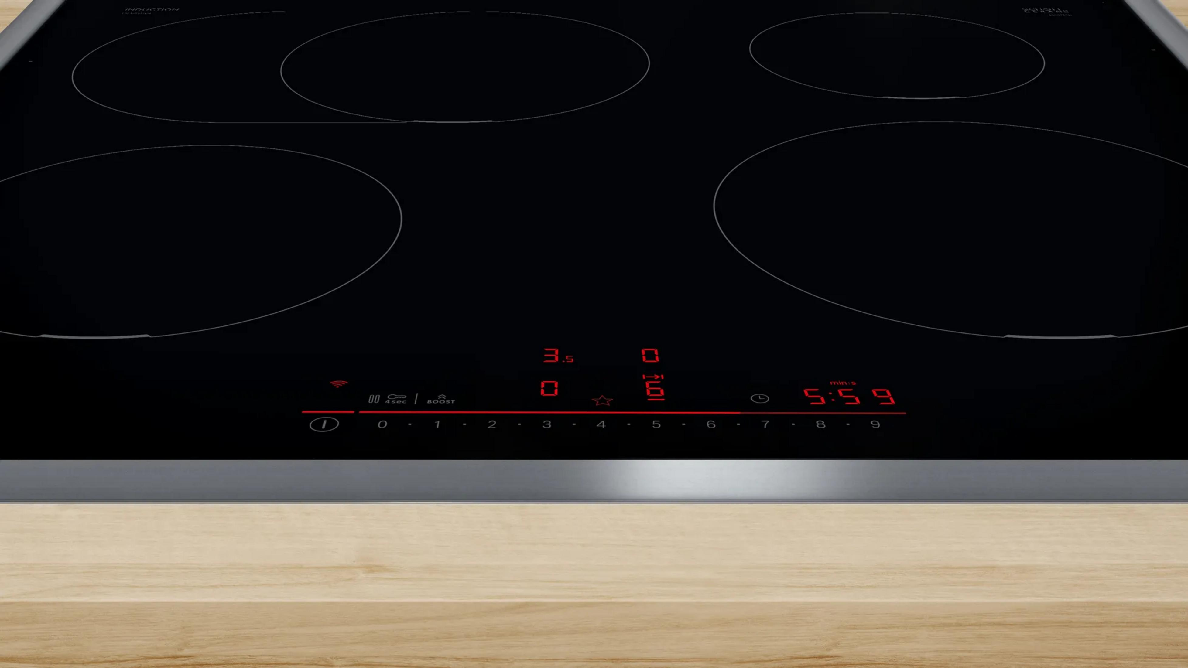 Plaque à induction noire avec quatre zones de cuisson et affichage numérique.