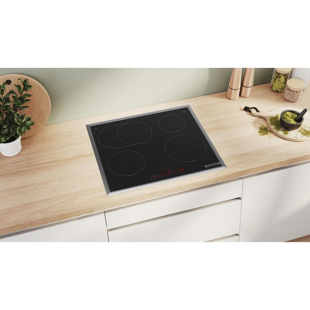 Une plaque à induction noire avec quatre zones de cuisson sur un plan de travail en bois.