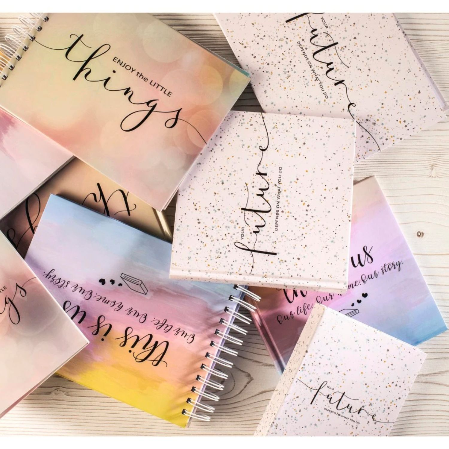 Kilka notatników z inspirującymi cytatami i kolorowymi tłami leży na drewnianym stole.