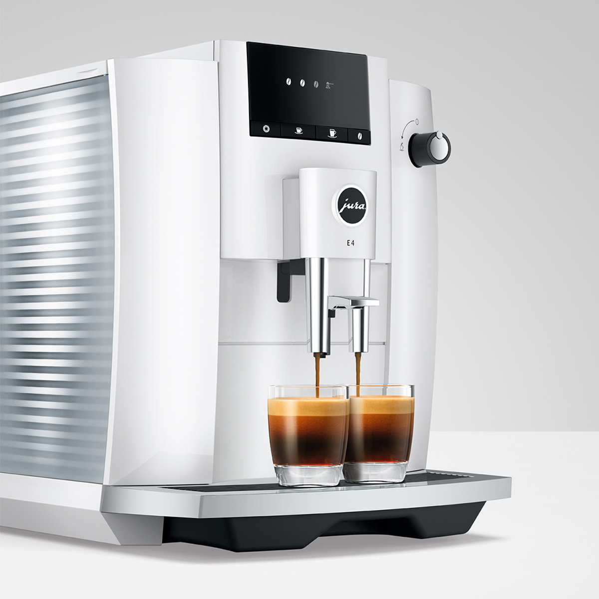 Una macchina da caffè bianca prepara due espresso in bicchieri.