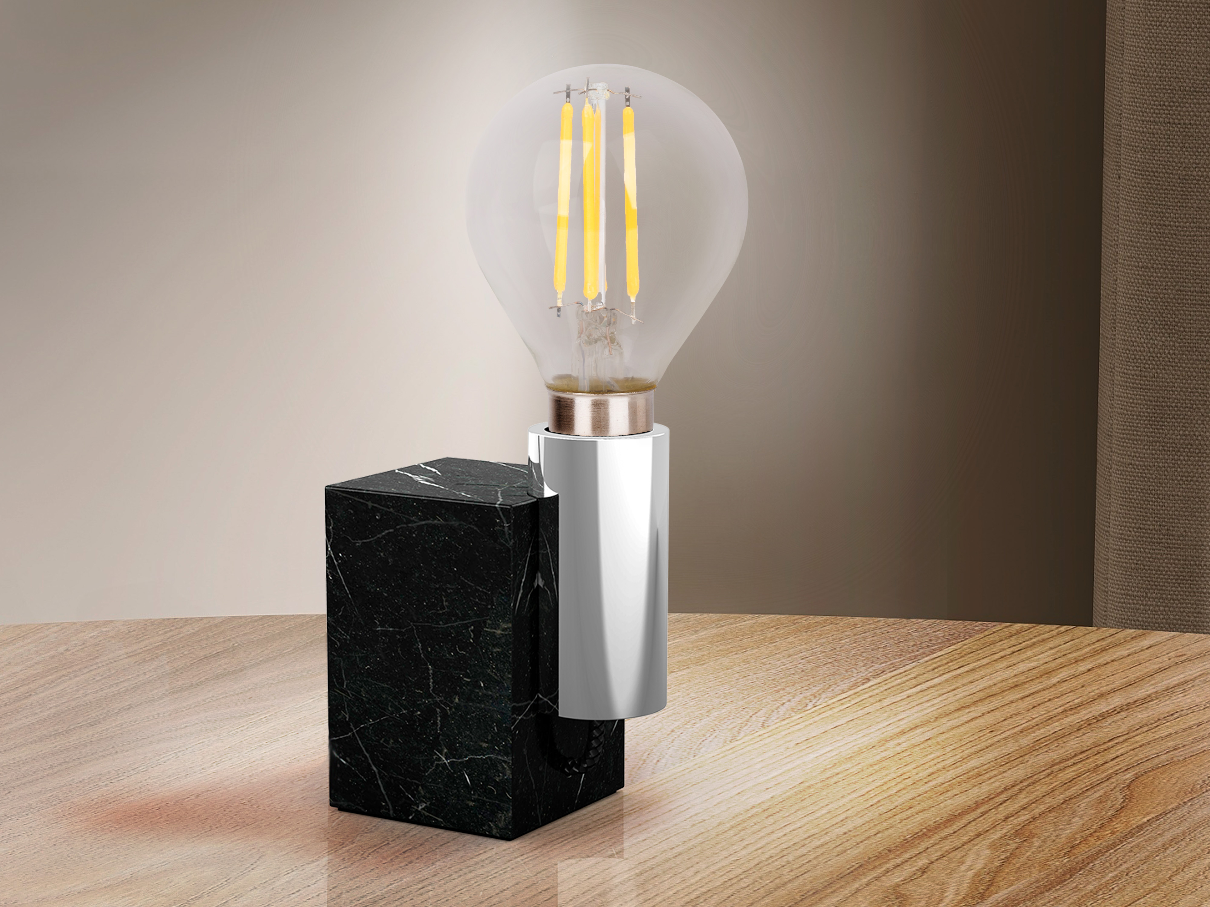 Eine Lampe mit schwarzem Marmorsockel und Glühfaden auf einem Holztisch.