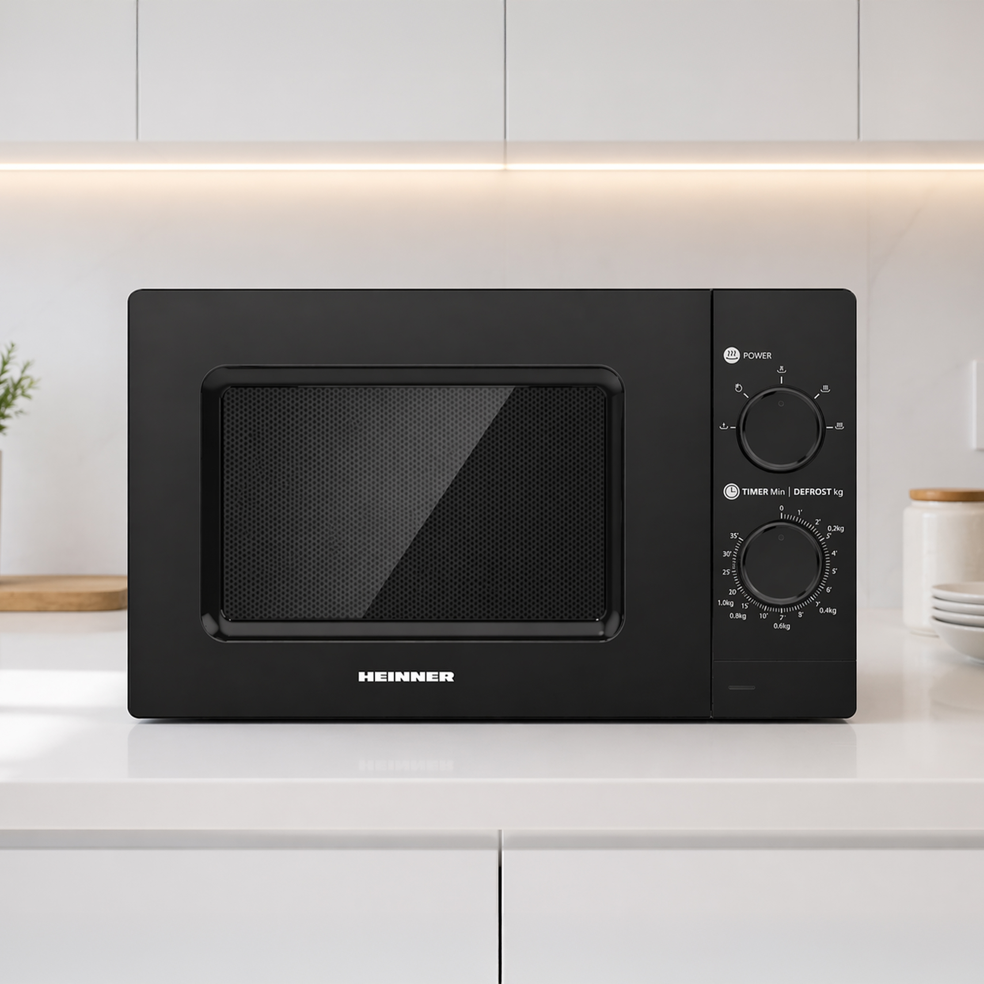 A black Heinner microwave oven with dials on a white countertop.