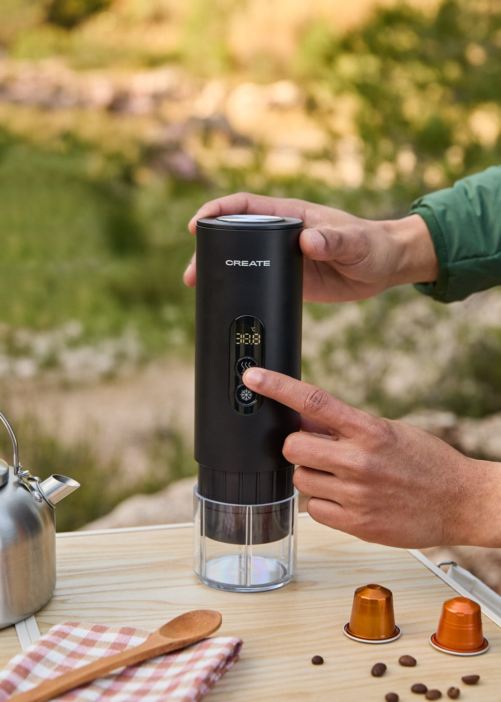 Una cafetera negra con pantalla, al aire libre. Manos operándola.