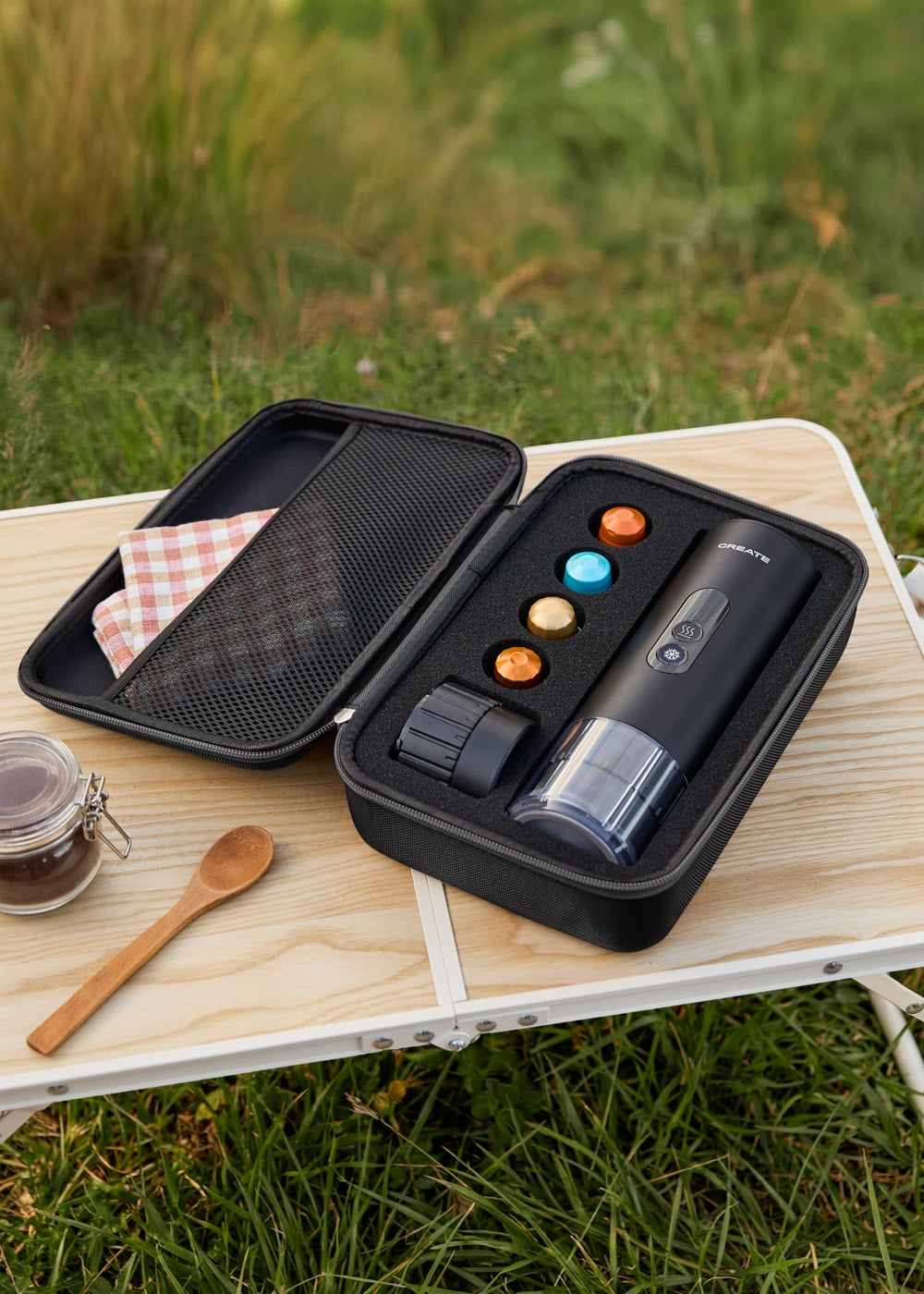 Un estuche negro con un sacacorchos eléctrico y accesorios sobre una mesa de madera exterior.