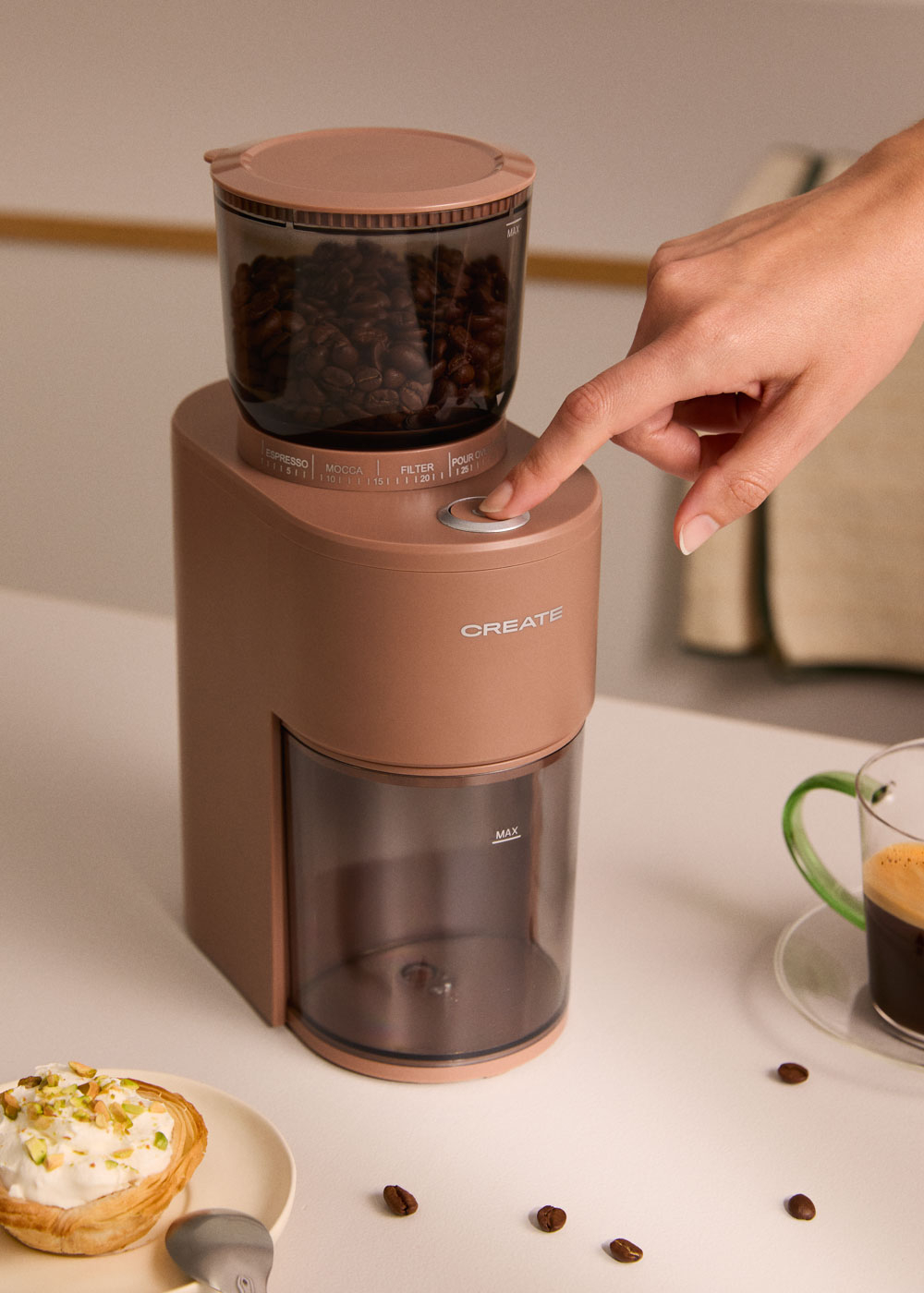 Una mano presiona el botón de un molinillo de café con granos.