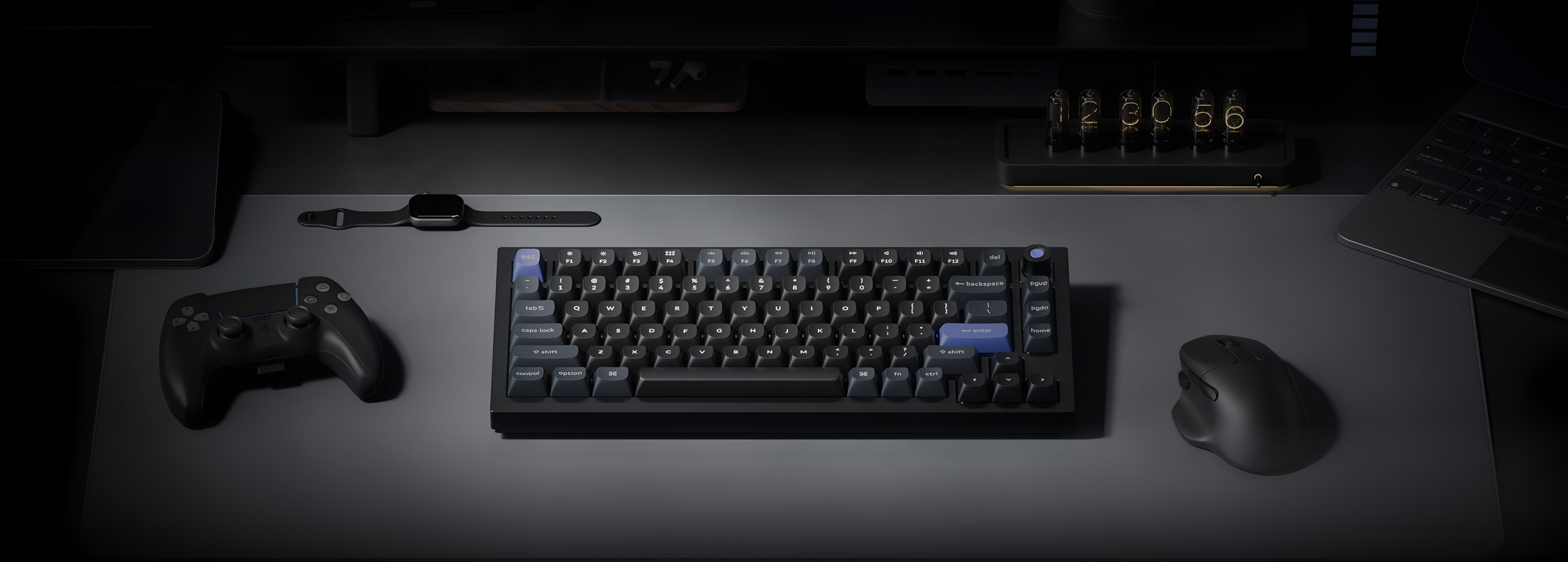 Ciemne stanowisko biurkowe z klawiaturą, myszą, padem, smartwatchem i laptopem.