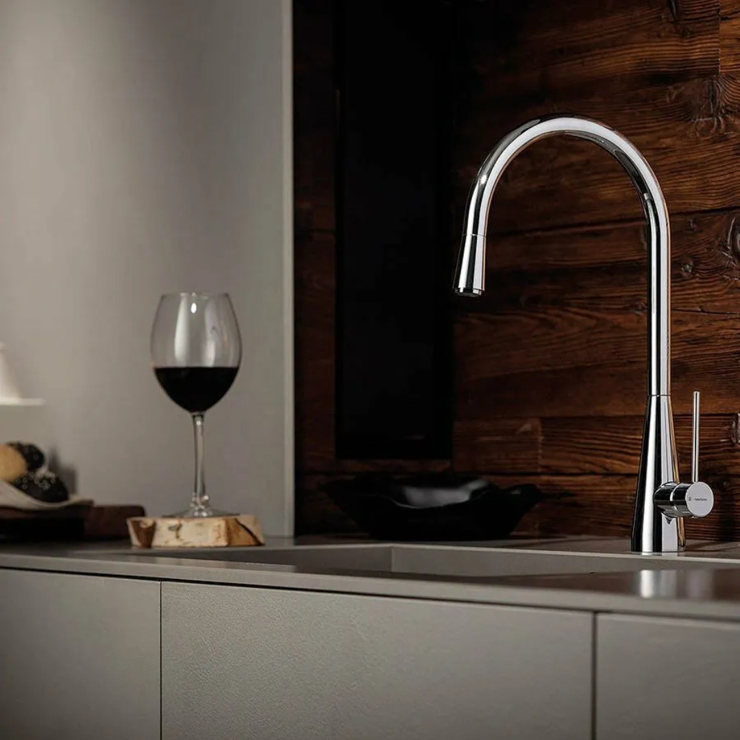 Un rubinetto da cucina moderno e un bicchiere di vino rosso su un bancone.