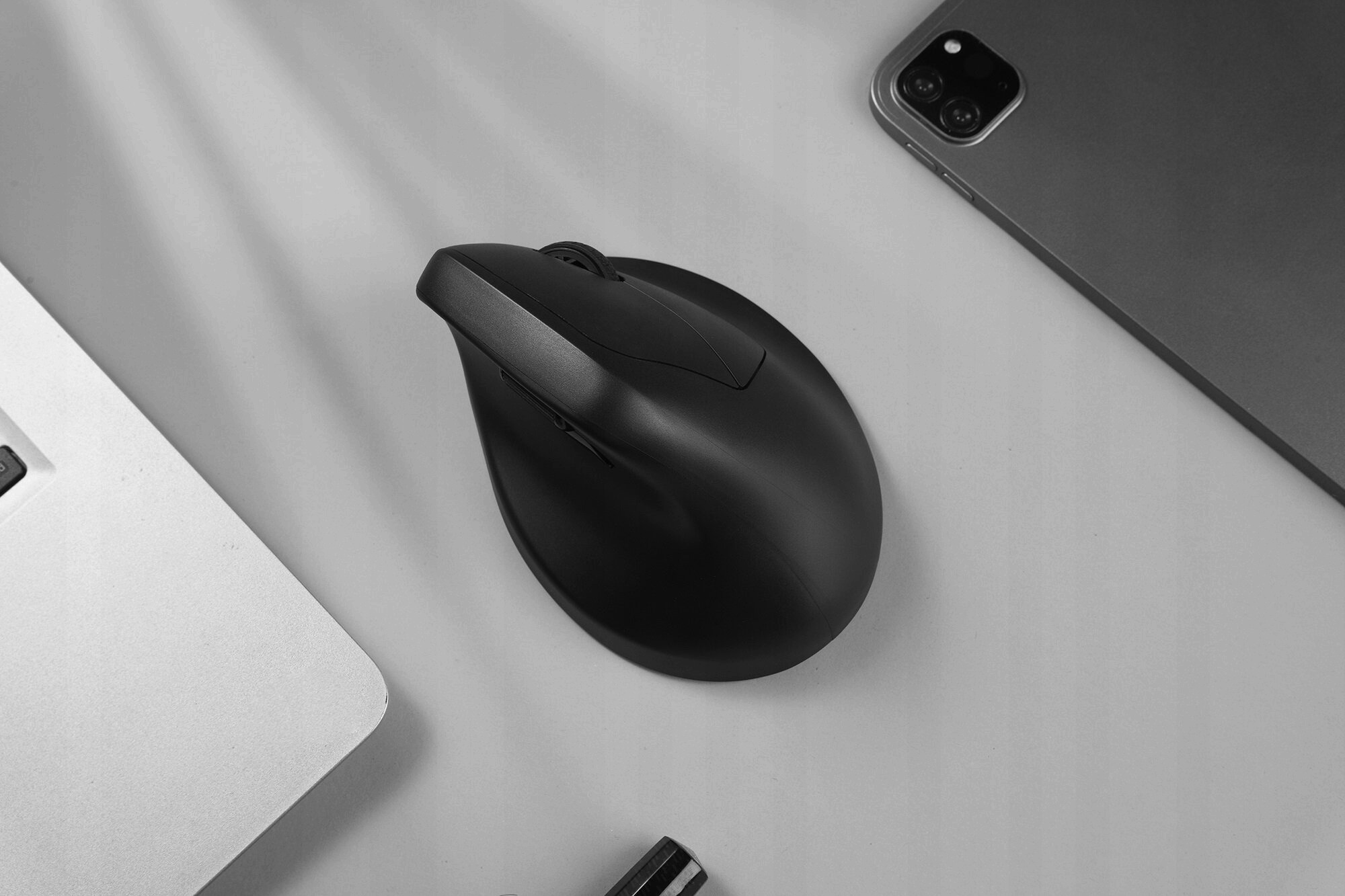 Czarna mysz obok laptopa i tabletu na jasnej powierzchni.