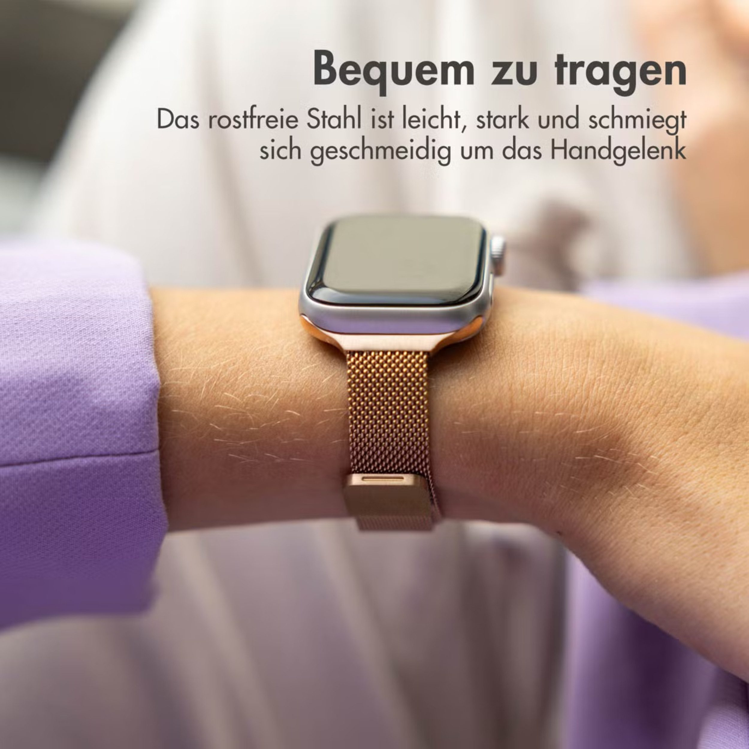 Eine roséfarbene Smartwatch mit Milanaise-Armband an einem Handgelenk.