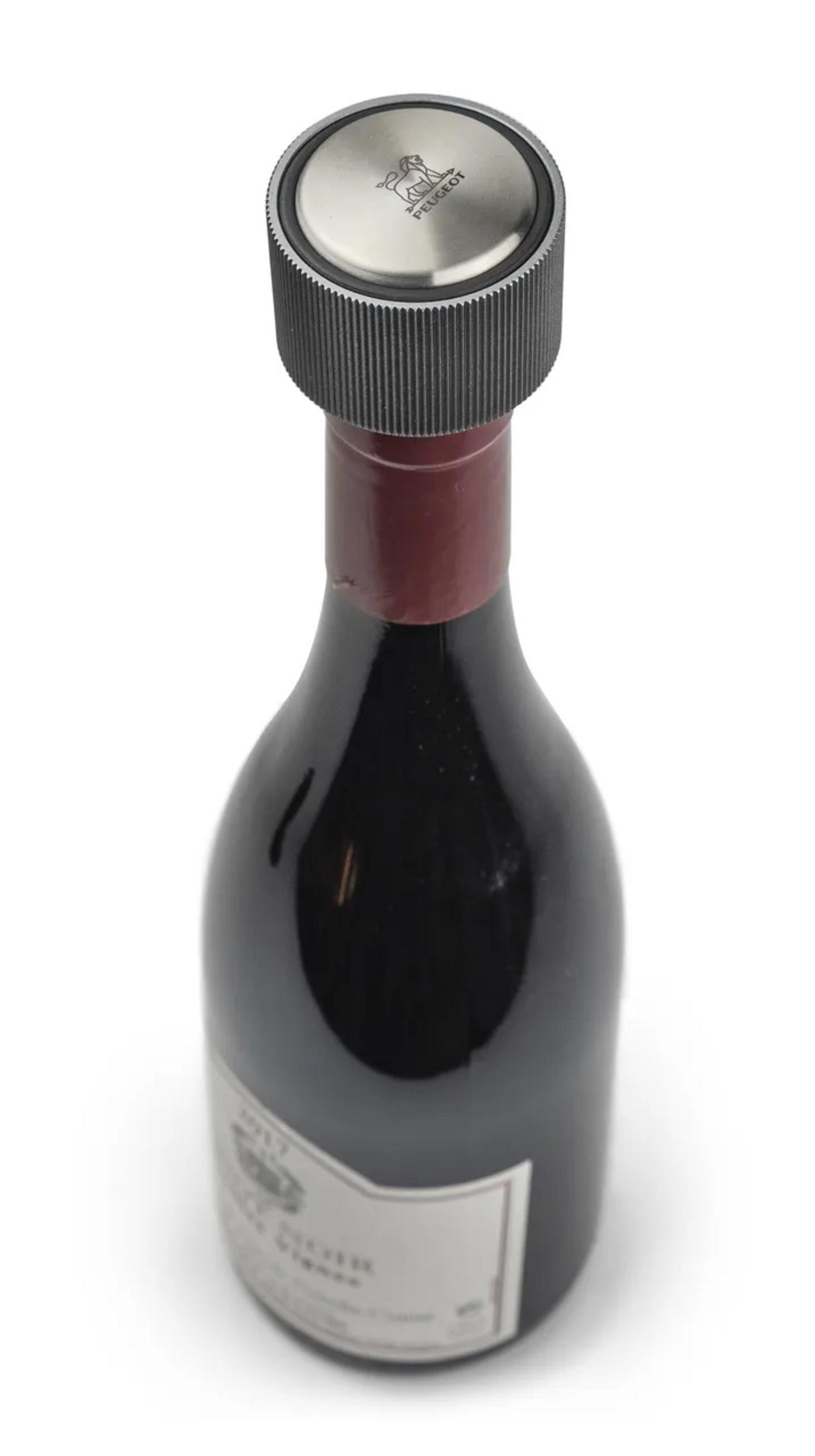 Una bottiglia di vino con bottiglia nera, sigillo rosso sul collo e tappo per bottiglia Peugeot argentato.