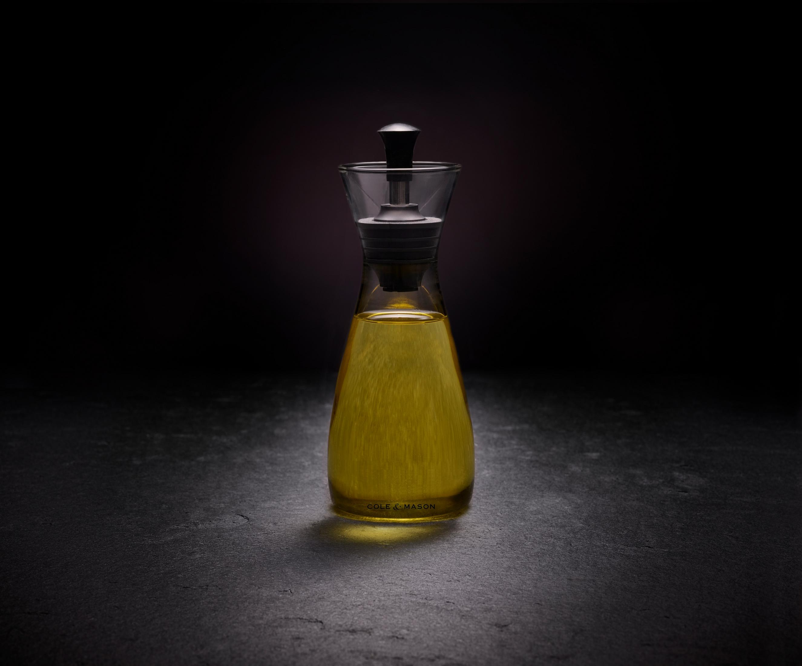 Eine Glasflasche mit gelbem Öl, Cole & Mason Marke, dunkler Hintergrund.