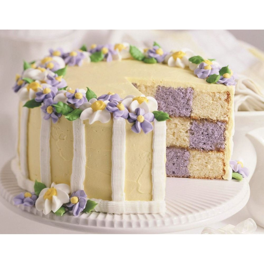 Ein cremefarbener Kuchen mit kariertem Inneren und Blumen-Dekoration.