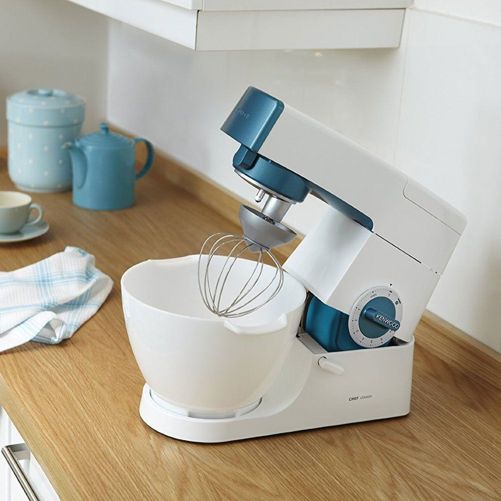 Eine weiße Kenwood Küchenmaschine mit blauem Akzent und Schneebesen in einer Schüssel.