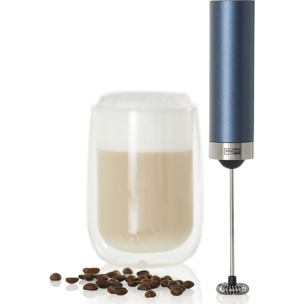 Un mousseur à lait bleu à côté d'un verre de lait mousseux et de grains de café.