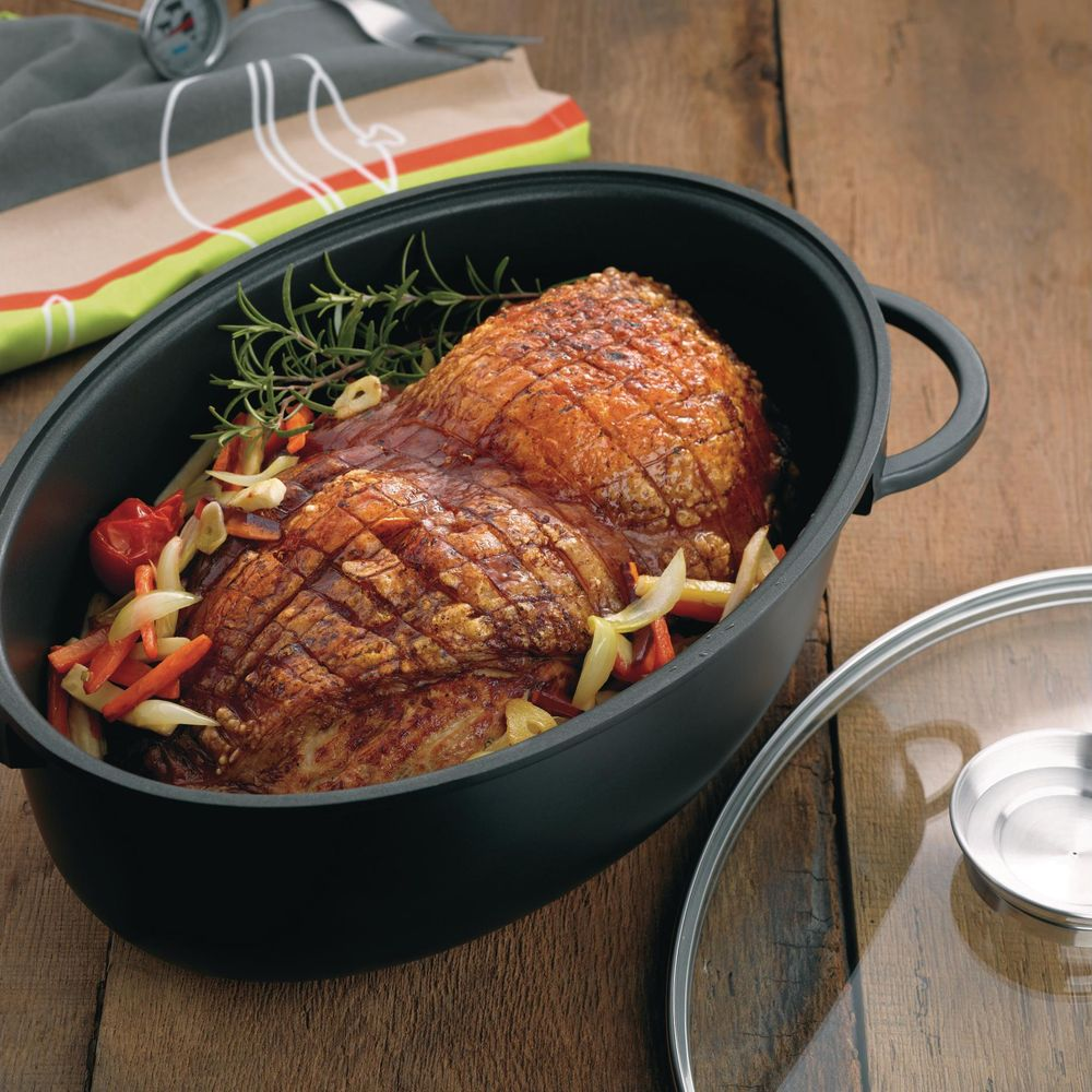 Viande rôtie avec légumes dans une cocotte ovale sur table en bois.