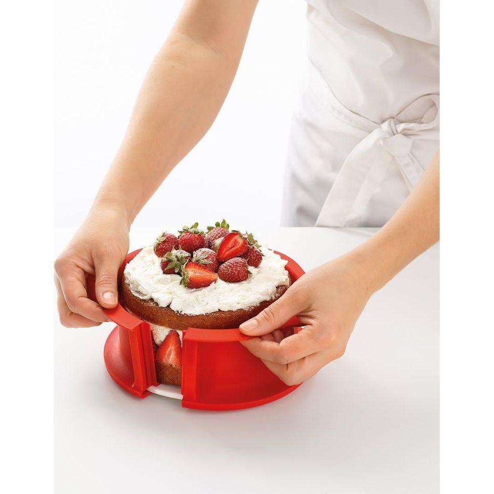 Ein Kuchen mit Sahne und Erdbeeren wird mit einem roten Tortenring geformt.