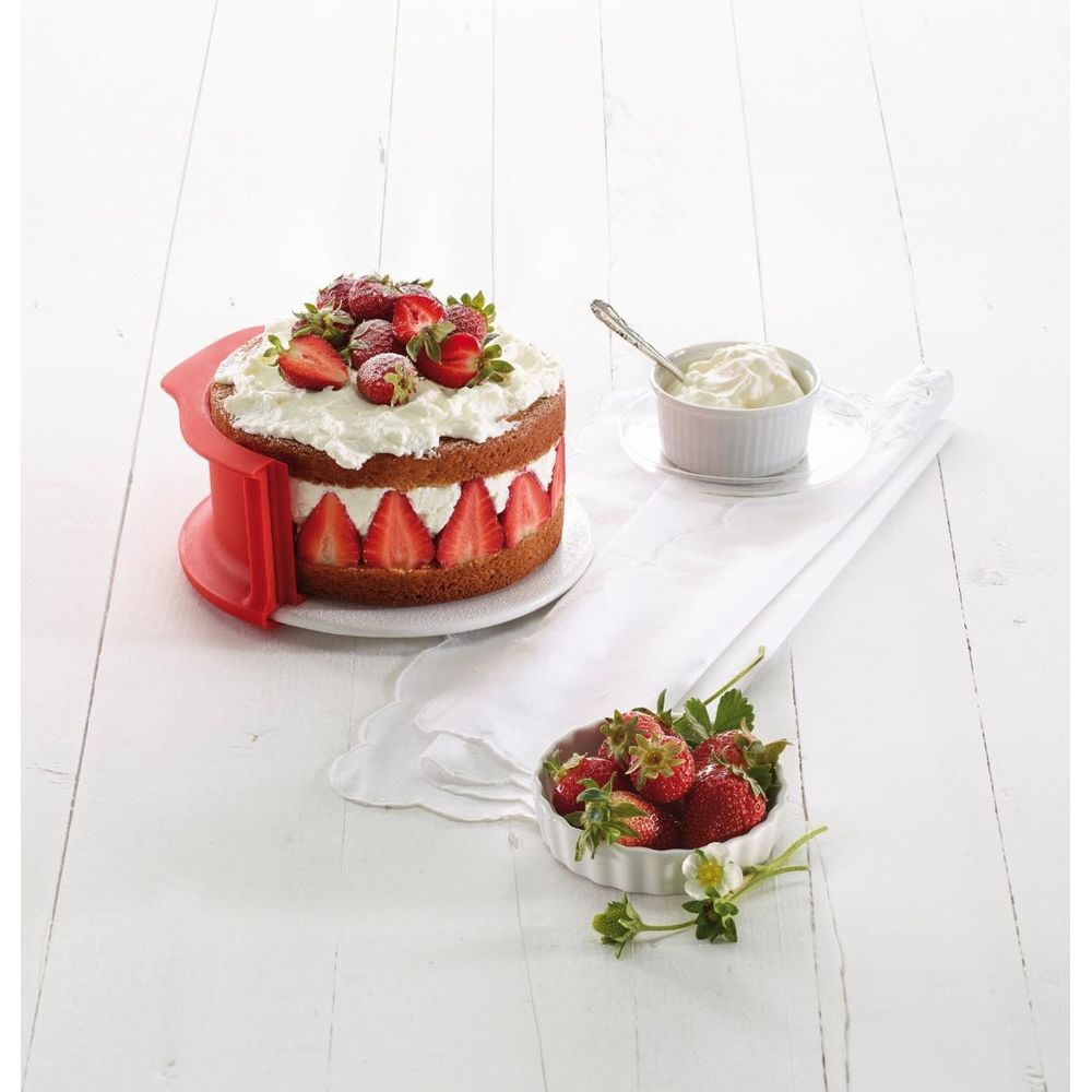 Ein Kuchen mit Sahne und Erdbeeren, daneben eine Schale mit Erdbeeren.