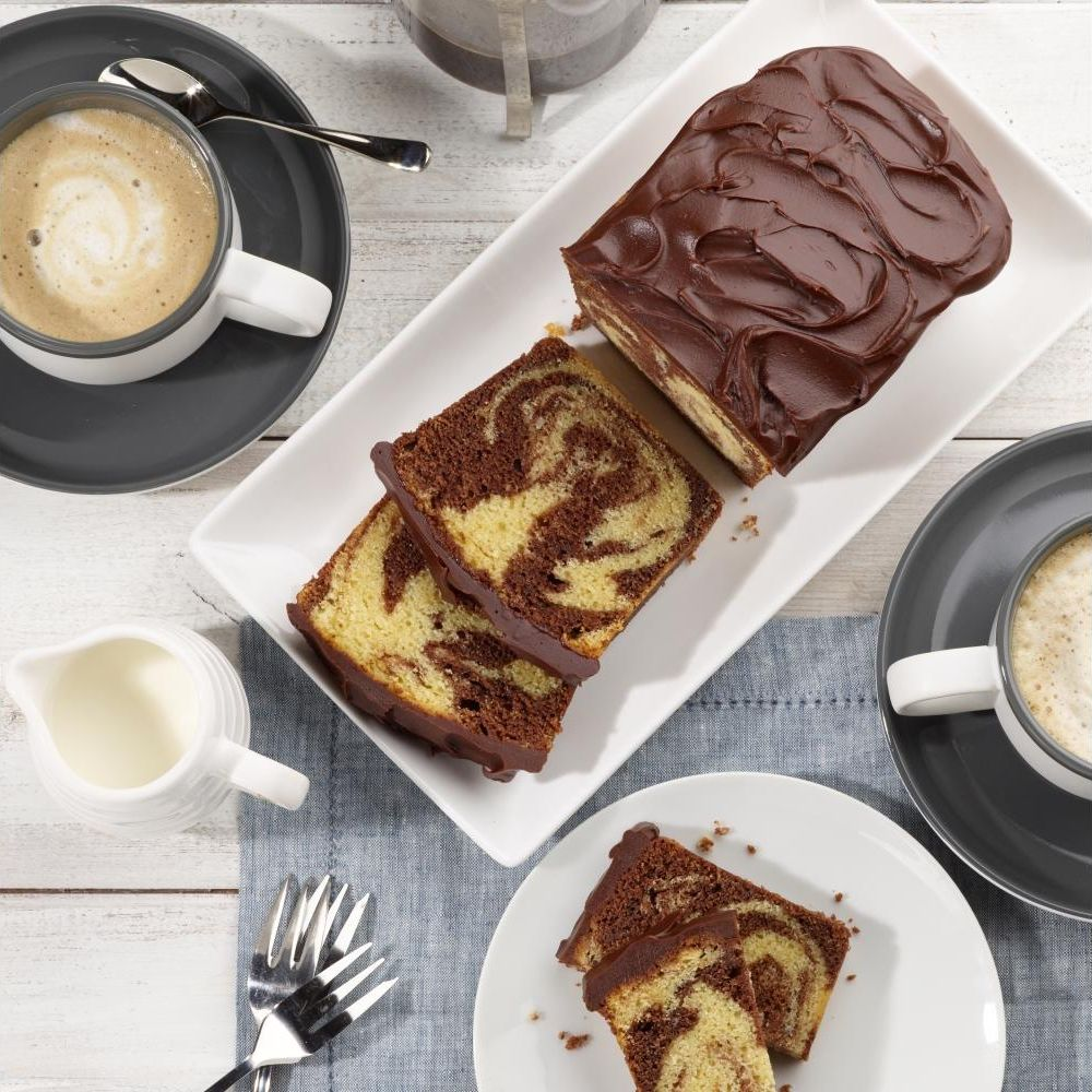 Marmor-Kuchen mit Schokoladenglasur, serviert mit Kaffee und Milch.