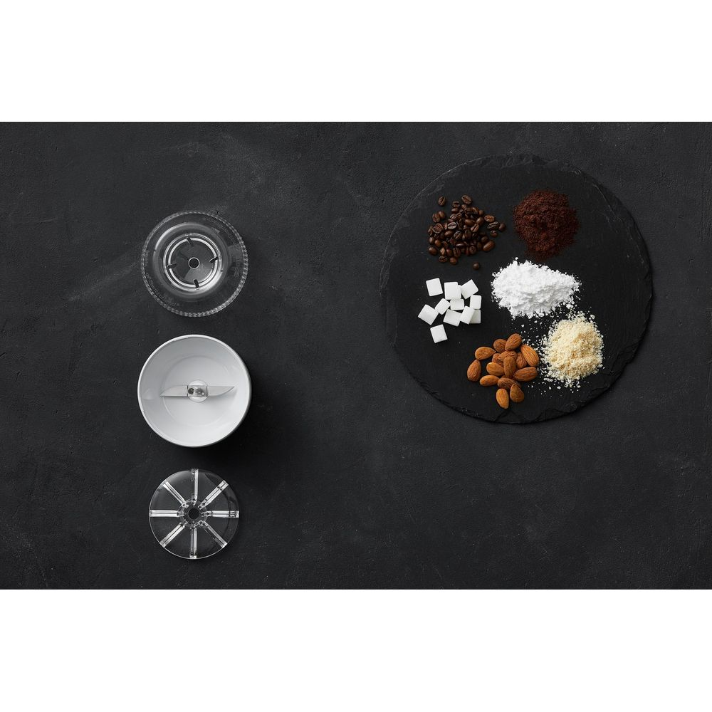 Kaffeebohnen, Zuckerwürfel, Puderzucker, Mandeln und Kaffeepulver auf schwarzem Stein.