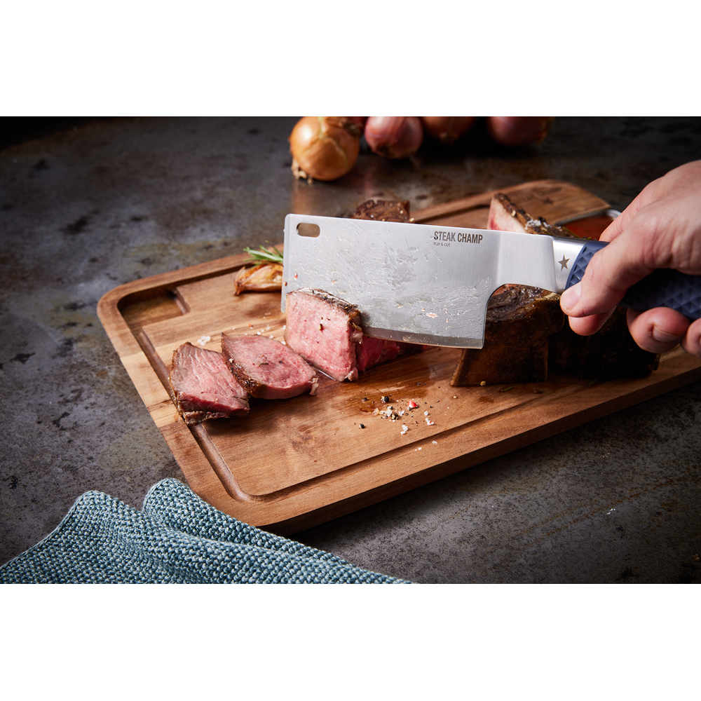 Un coltello taglia una bistecca sanguinante su un tagliere di legno. Cipolle sullo sfondo.